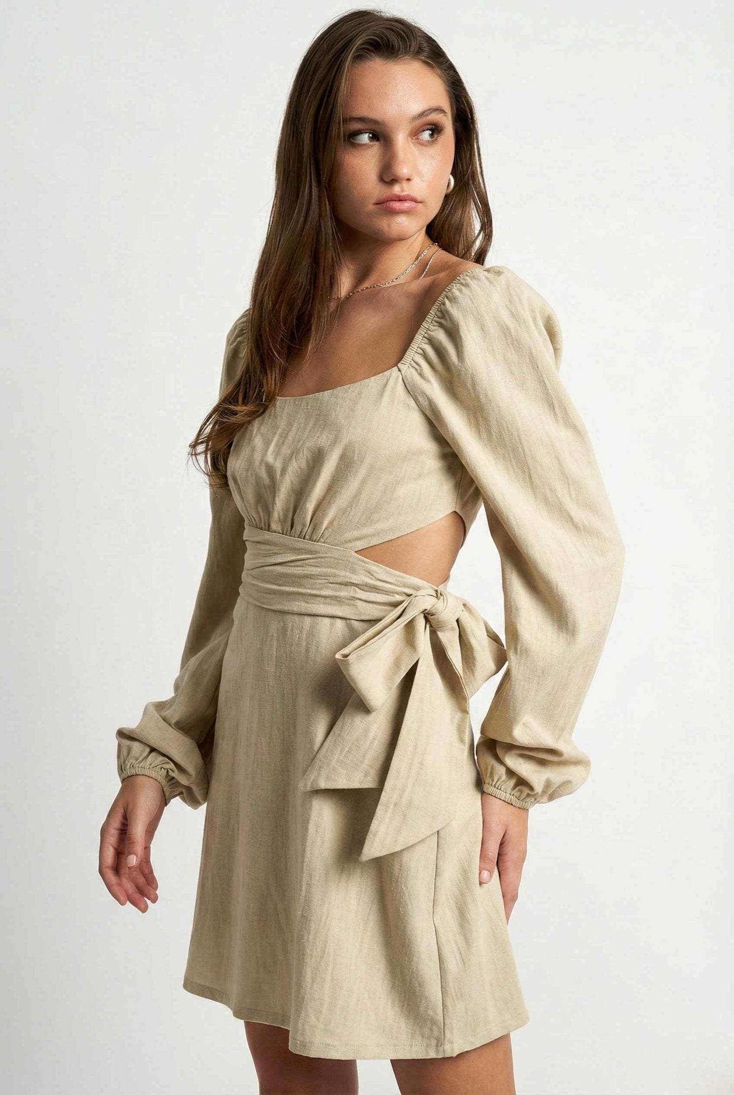 Woman wearing a Aurelia Mini Sage Long Sleeve Cutout Dress with cut-out design and bow detail