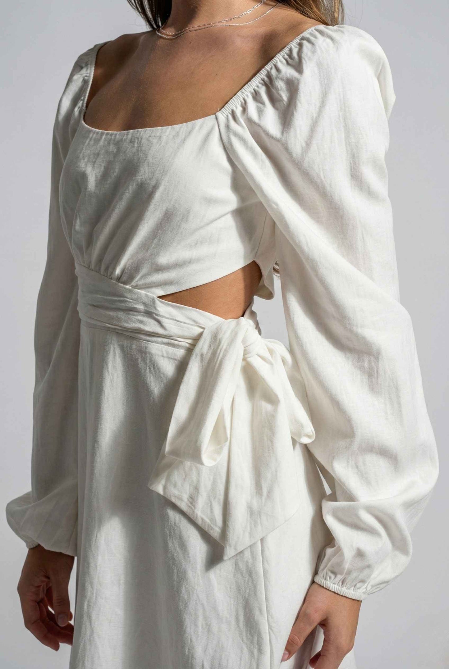 Woman wearing a Aurelia Mini White Long Sleeve Cutout Dress on a plain background