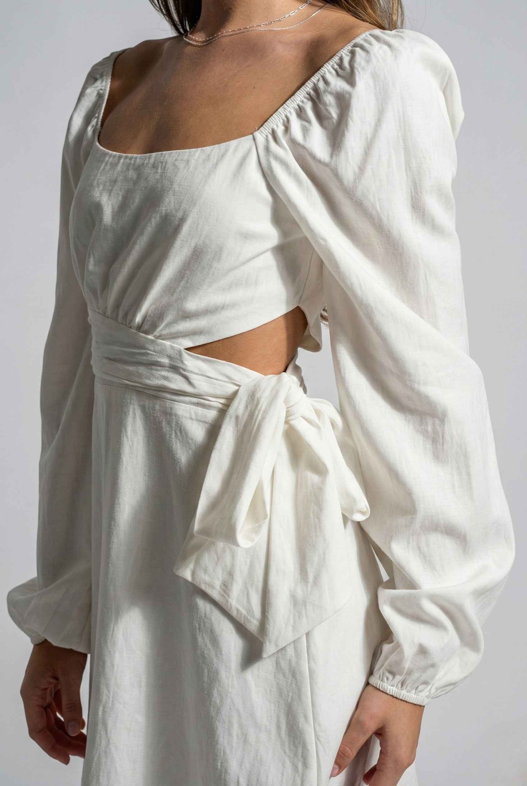 Woman wearing a Aurelia Mini White Long Sleeve Cutout Dress on a plain background