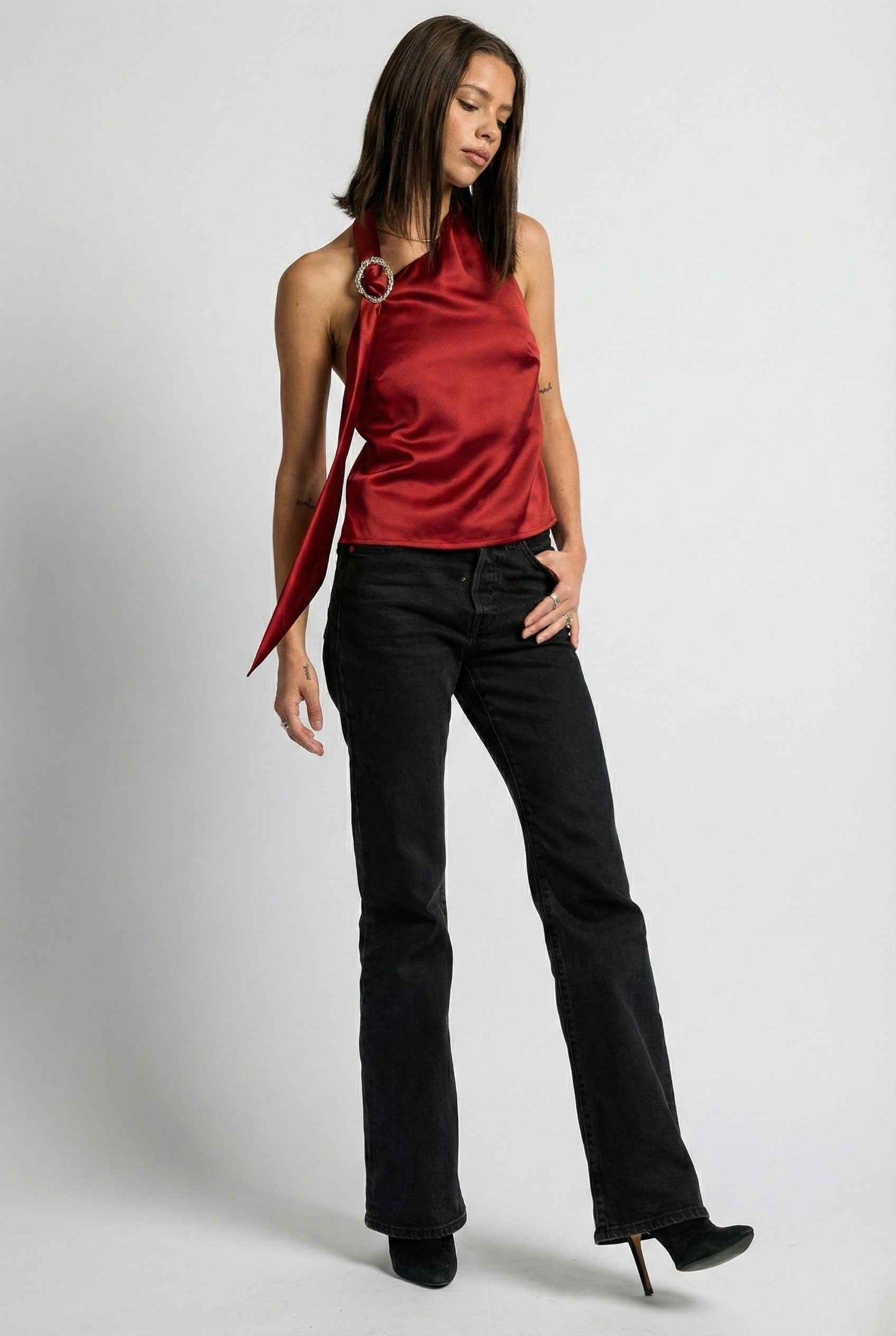 Woman wearing a Aurelia Top Burgundy Satin One-Shoulder Scarf Blouse and black pants on a white background