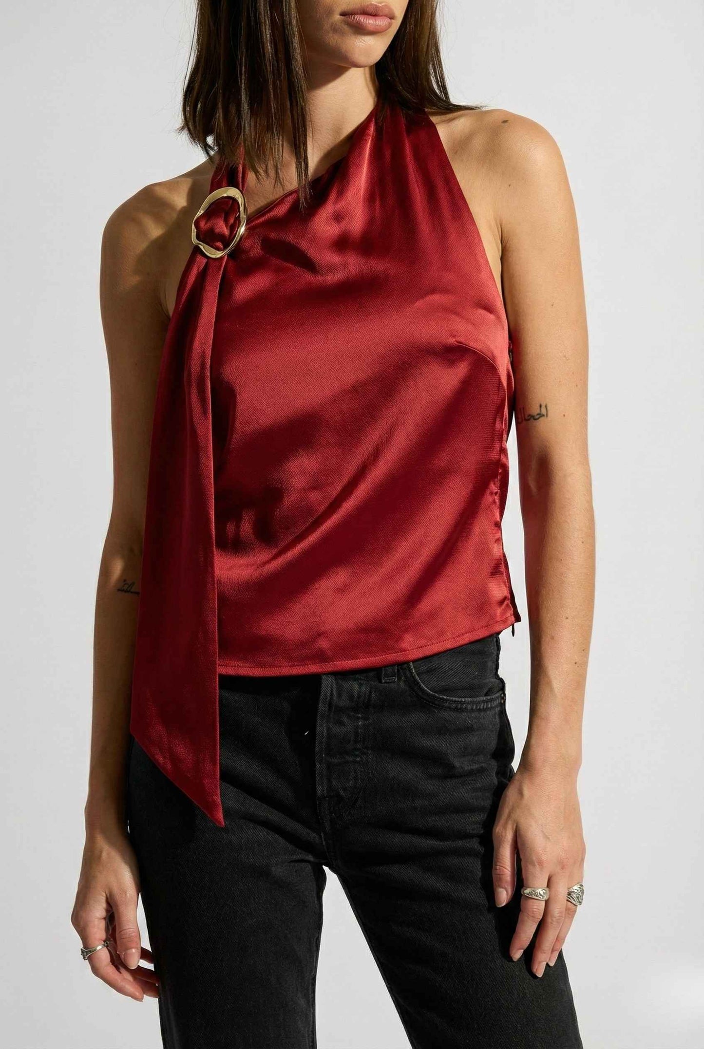 Woman wearing a Aurelia Top Burgundy Satin One-Shoulder Scarf Blouse and black pants on a white background