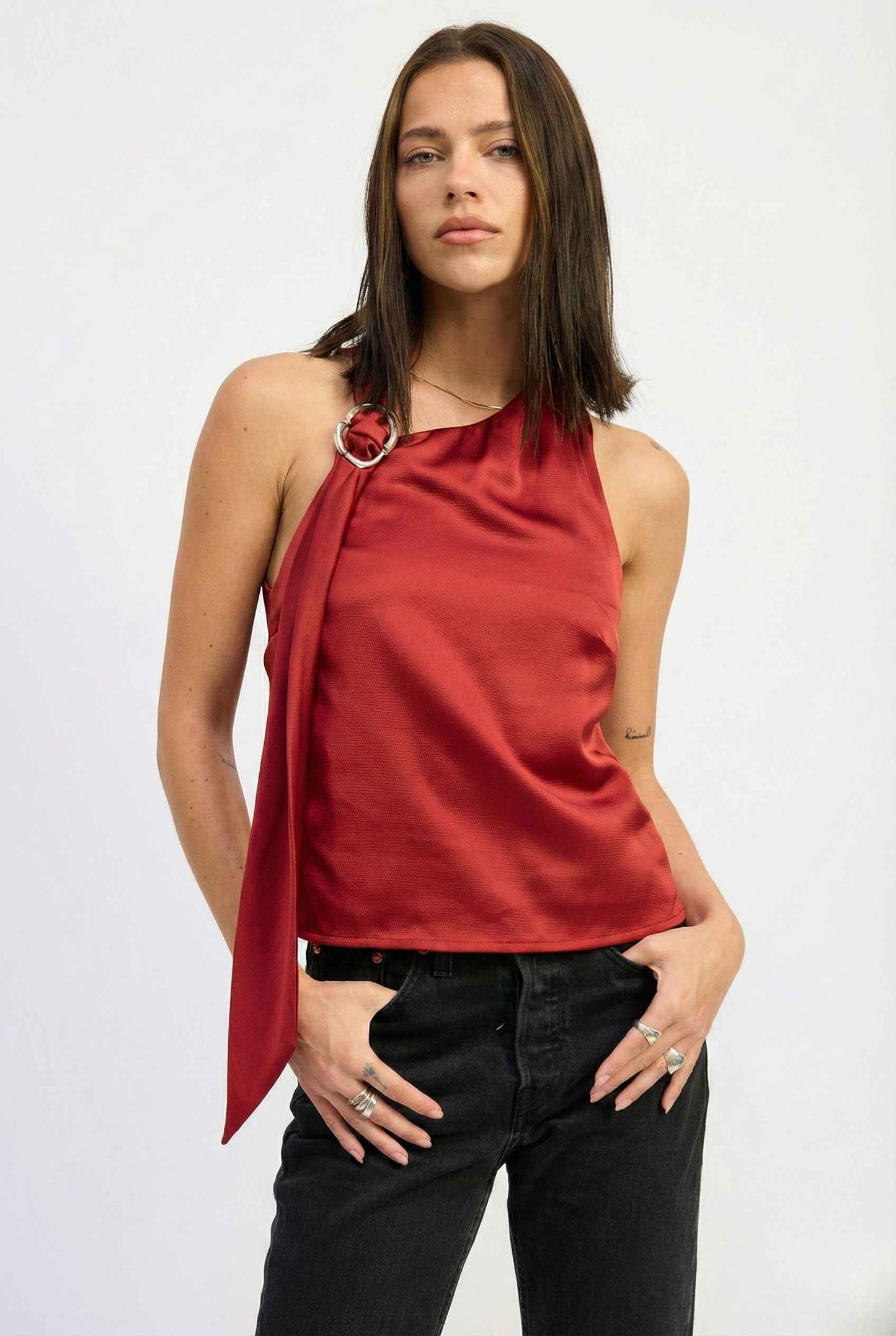 Woman wearing a Aurelia Top Burgundy Satin One-Shoulder Scarf Blouse and black pants on a white background