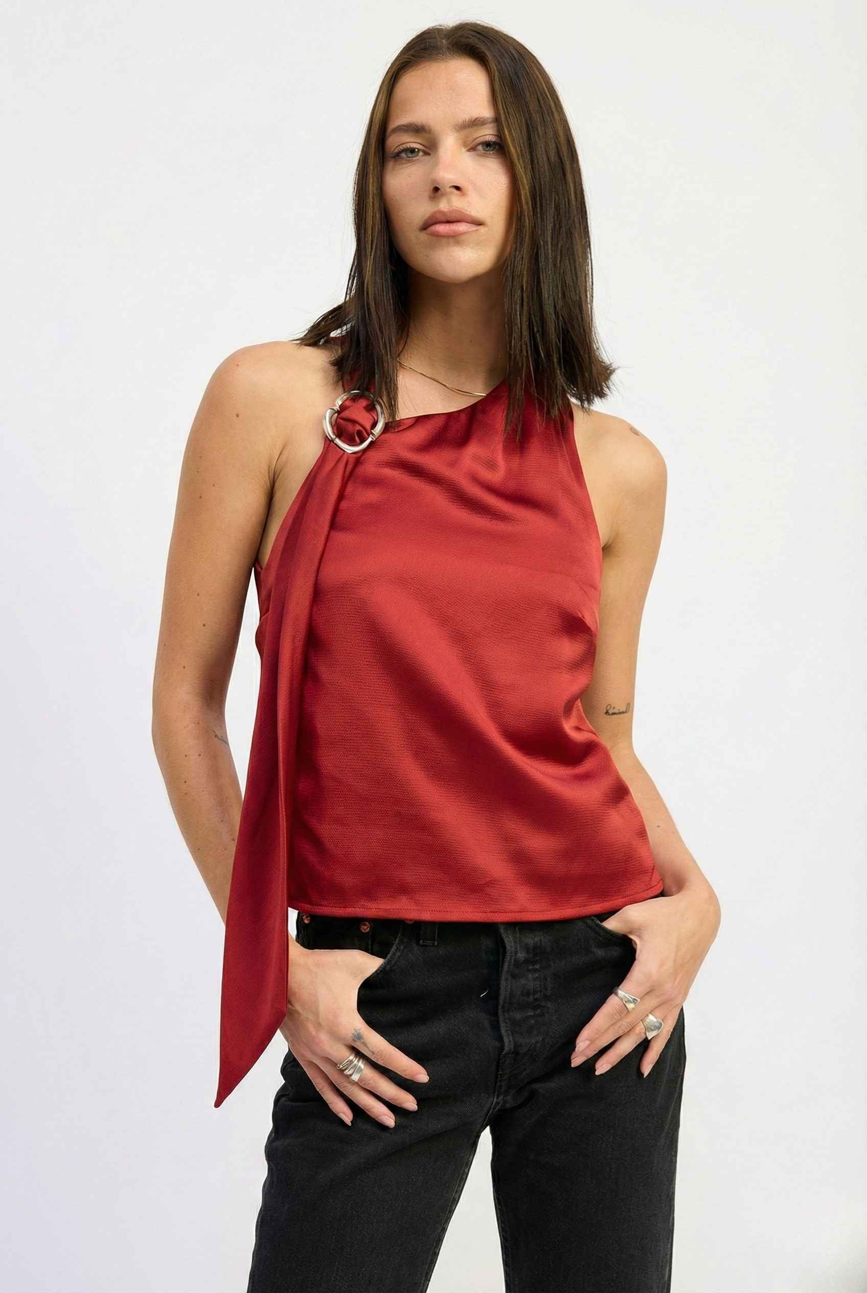 Woman wearing a Aurelia Top Burgundy Satin One-Shoulder Scarf Blouse and black pants on a white background