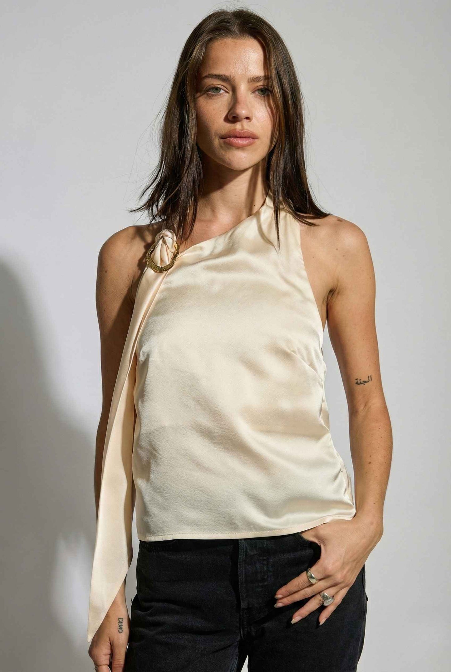 Woman wearing a Aurelia Top Ivory Satin One-Shoulder Scarf Blouse with a white background