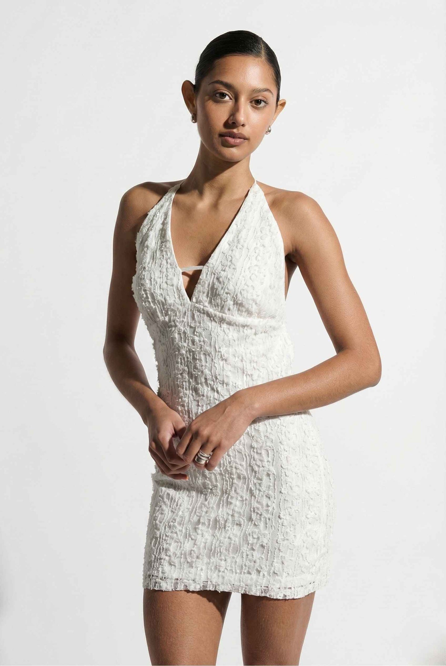 Woman wearing a Bianca Mini Ivory Sequin Plunge Halter Dress against a plain background