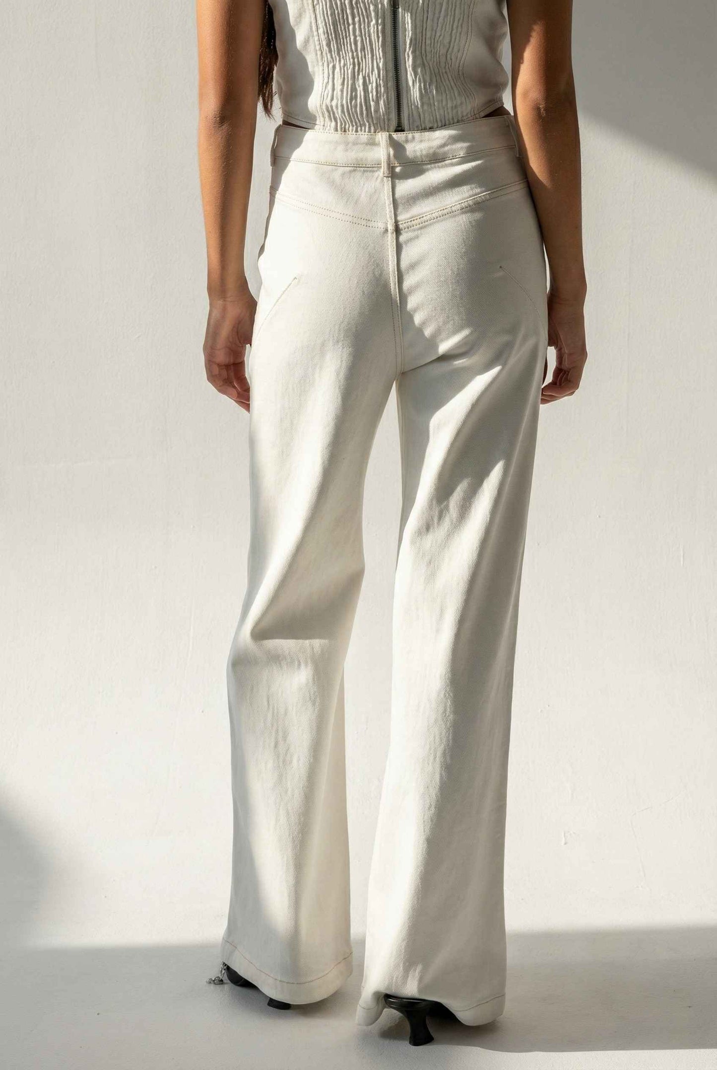 Model wearing Bianca Pants in Off White Cotton-Stretch Seamed Wide-Leg Trousers with matching corset top and heels against plain backdrop