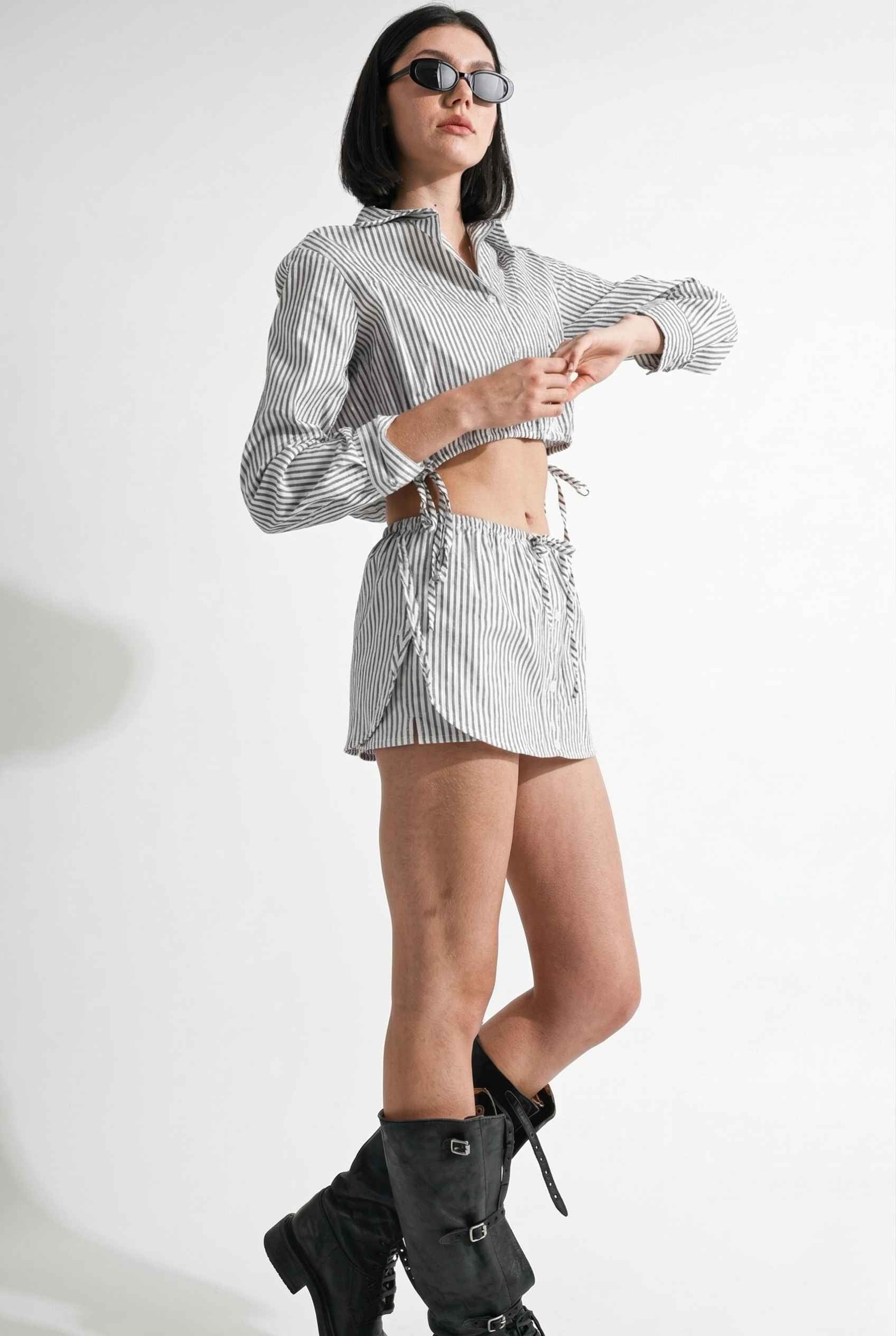 Woman wearing a striped shirt and Blair Skort White Striped Poplin Mini Skort with Shirttail Hem with knee-high boots on a white background