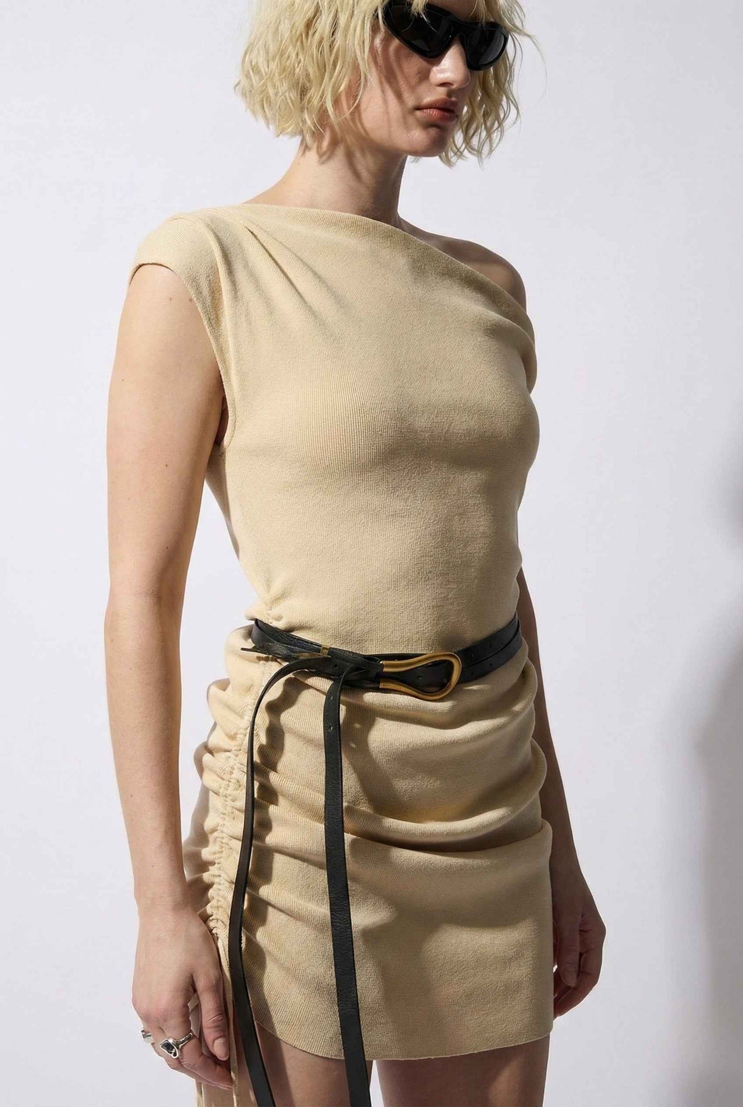 Woman wearing a Blaire Mini Cream Off-Shoulder Ruched Dress with a black belt against a white background