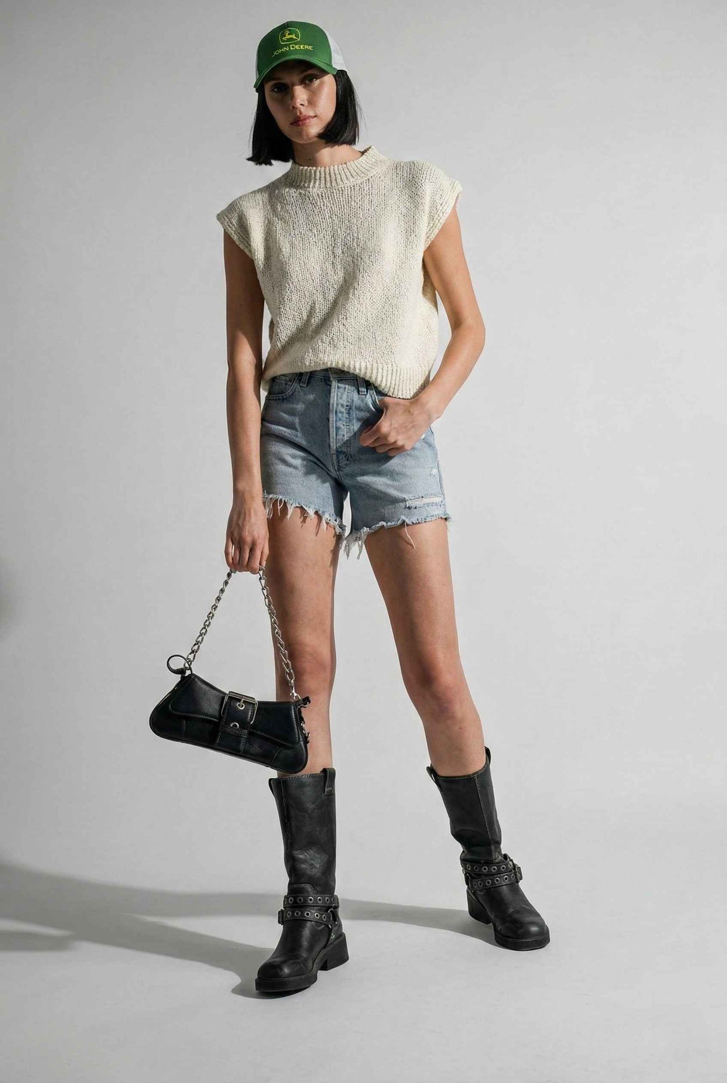 Model wearing Blaire Top in Off White Textured Knit Sleeveless Muscle Tee with denim shorts and tall boots on a plain background