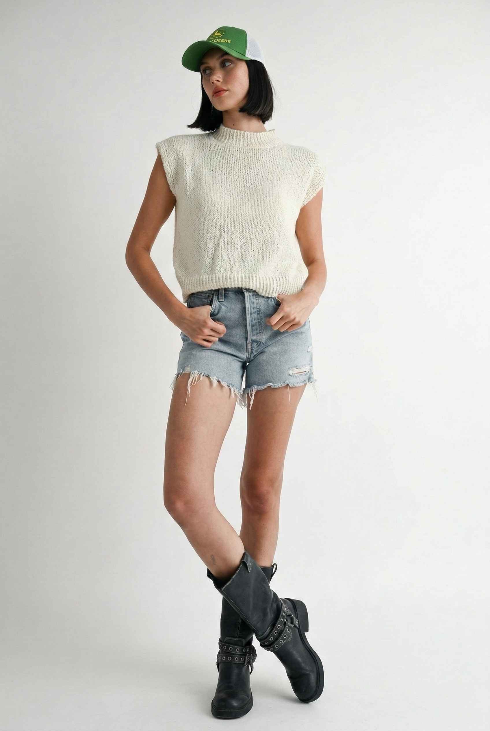 Model wearing Blaire Top in Off White Textured Knit Sleeveless Muscle Tee with denim shorts and tall boots on a plain background