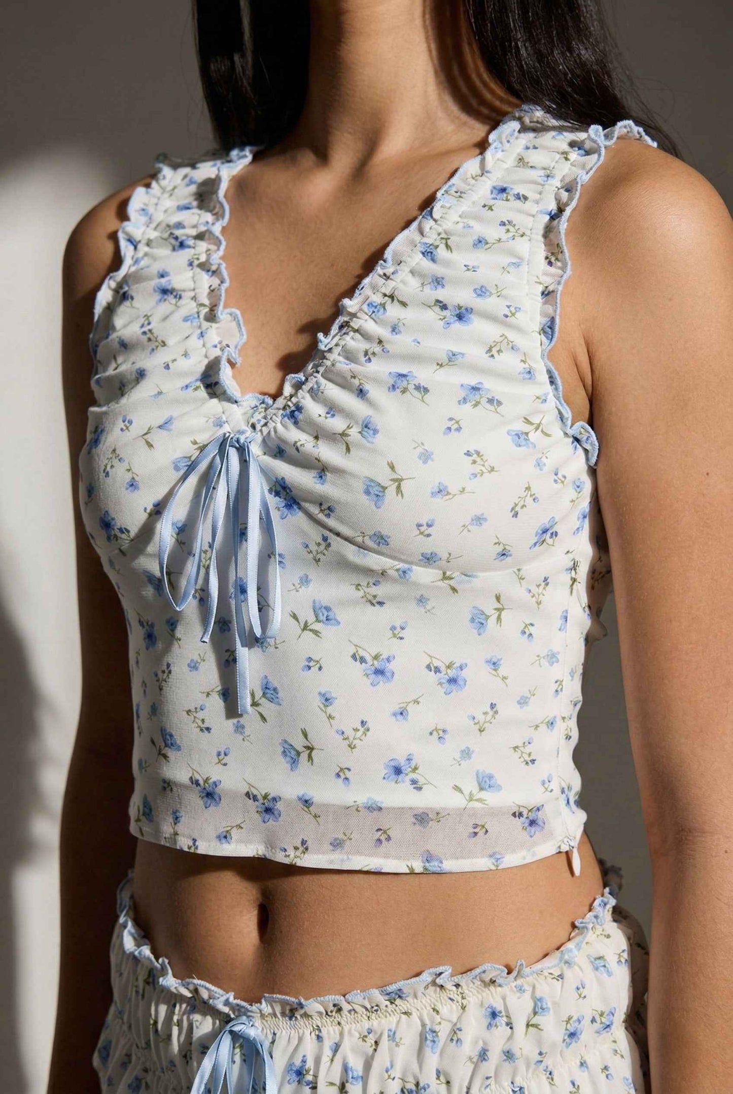 Woman wearing a Callie Top White & Light Blue Floral Ruffle Tie-Front Cami with ruffled details