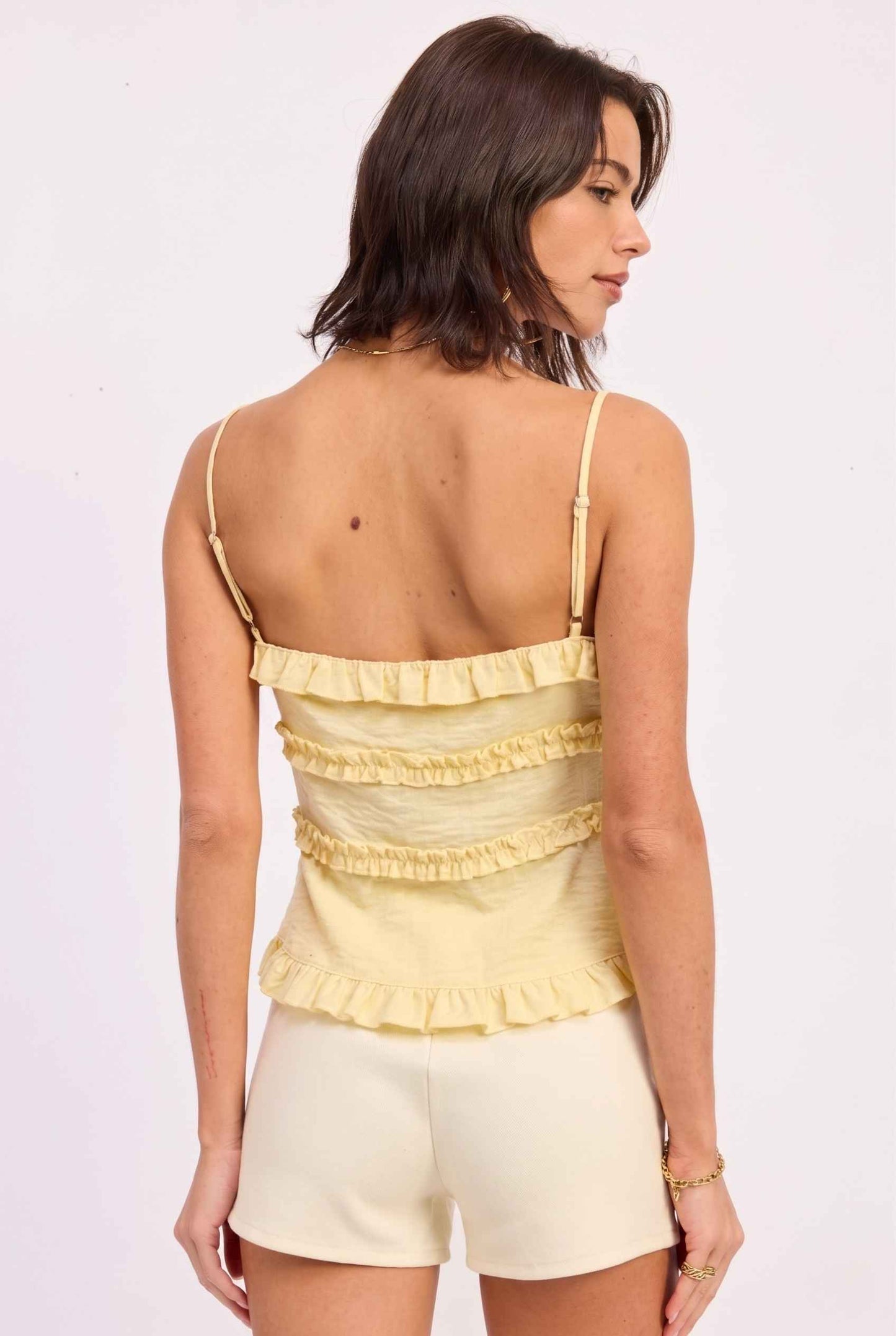 Model wearing Camille Ruffle Tie-Front Top in Yellow Tiered Sleeveless Blouse paired with micro shorts close back view