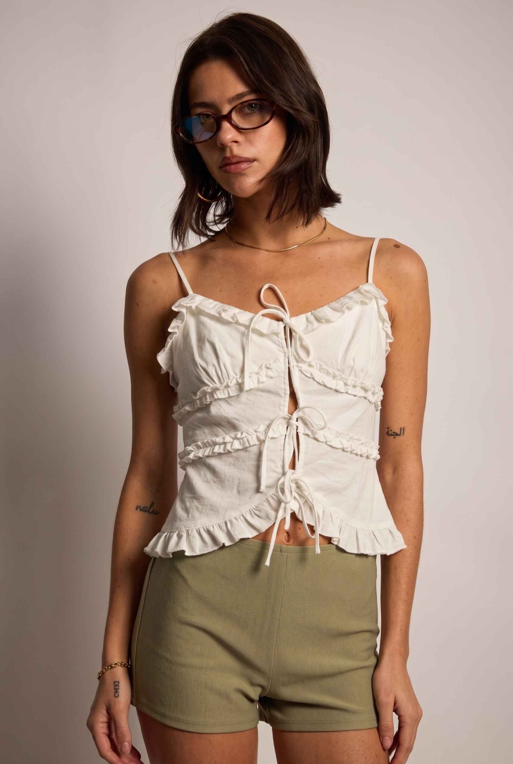 Model wearing Camille Ruffle Tie-Front Top in White Tiered Sleeveless Blouse paired with micro shorts close up ruffle details
