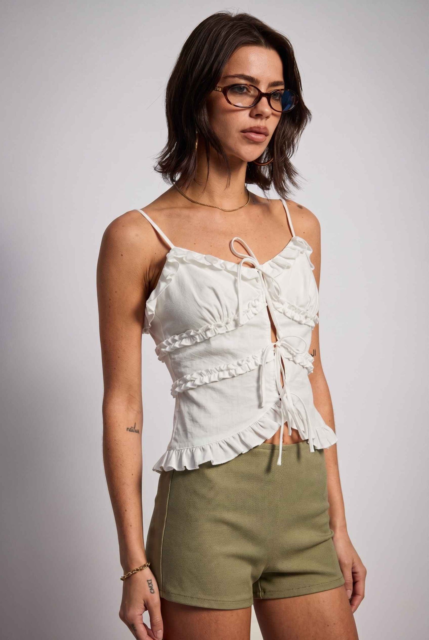 Model wearing Camille Ruffle Tie-Front Top in White Tiered Sleeveless Blouse paired with micro shorts  close up side