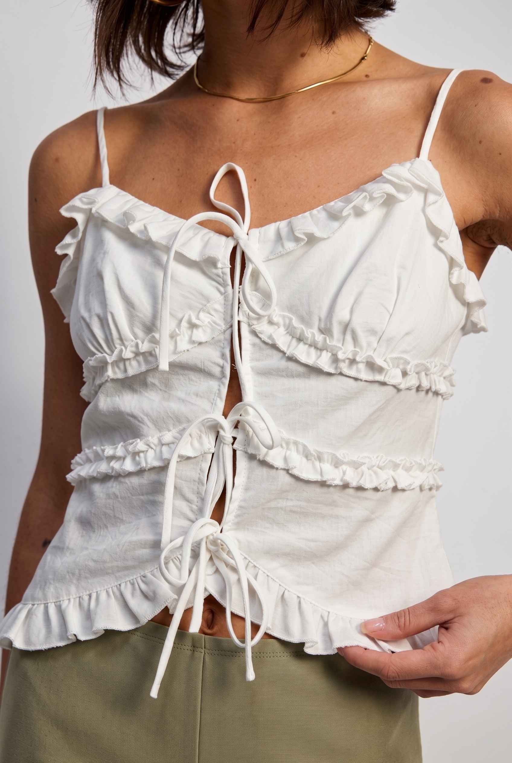 Model wearing Camille Ruffle Tie-Front Top in White Tiered Sleeveless Blouse paired with micro shorts close up tied front detail