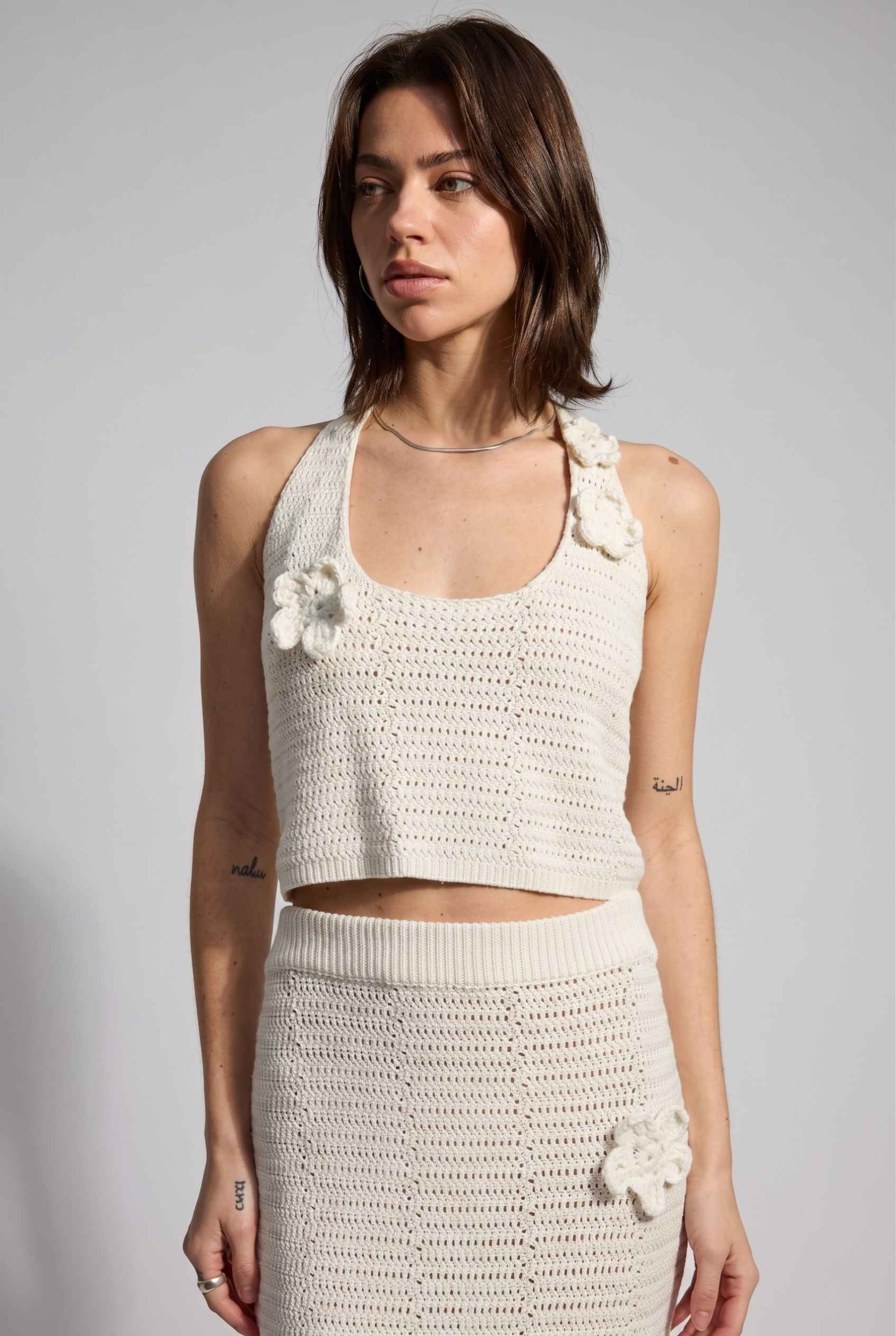 Model wearing Capri Floral Crochet Halter Top in Ivory Cotton Knit Crop Top with matching maxi skirt close up applique detail
