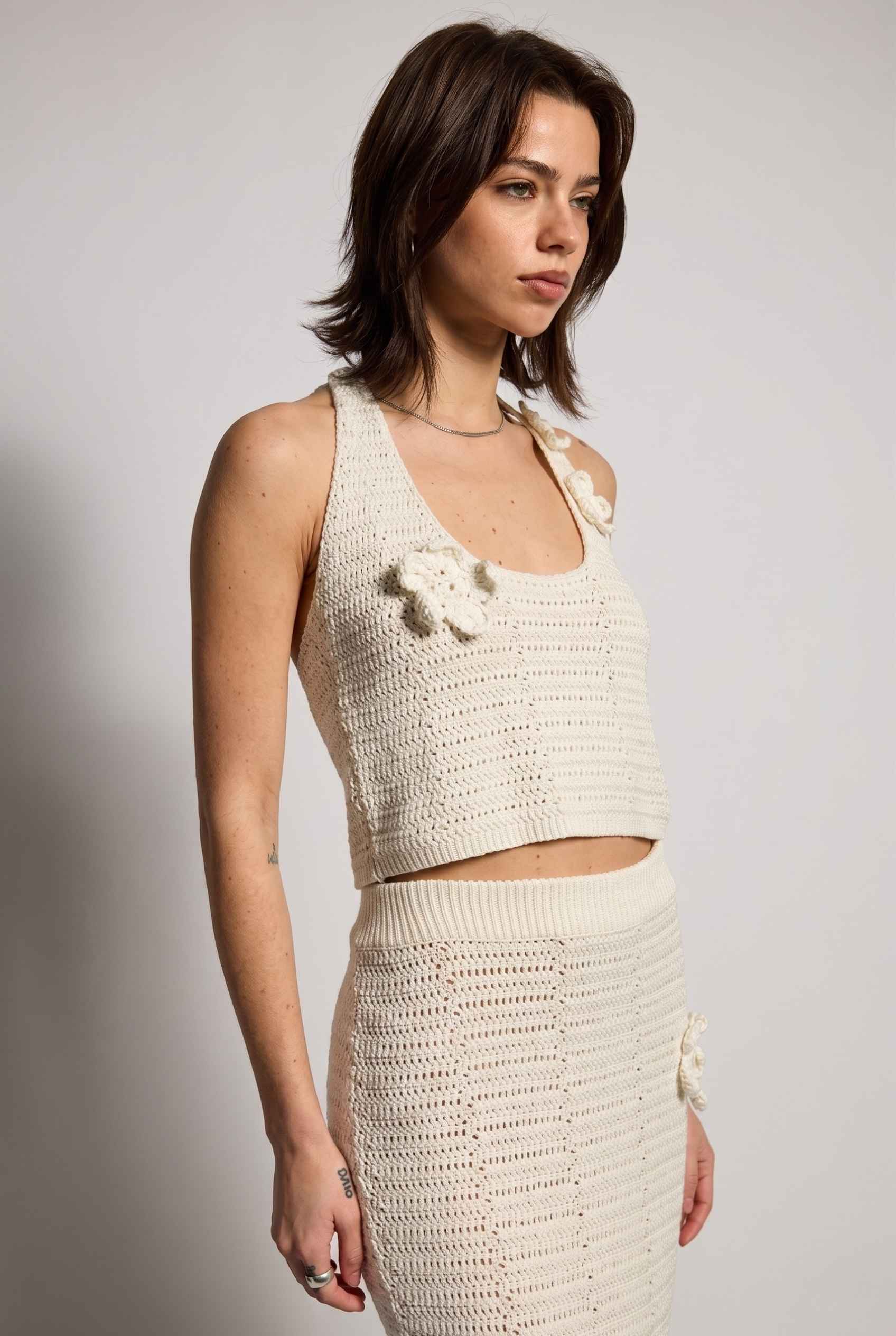 Model wearing Capri Floral Crochet Halter Top in Ivory Cotton Knit Crop Top with matching maxi skirt close up crochet knit detail