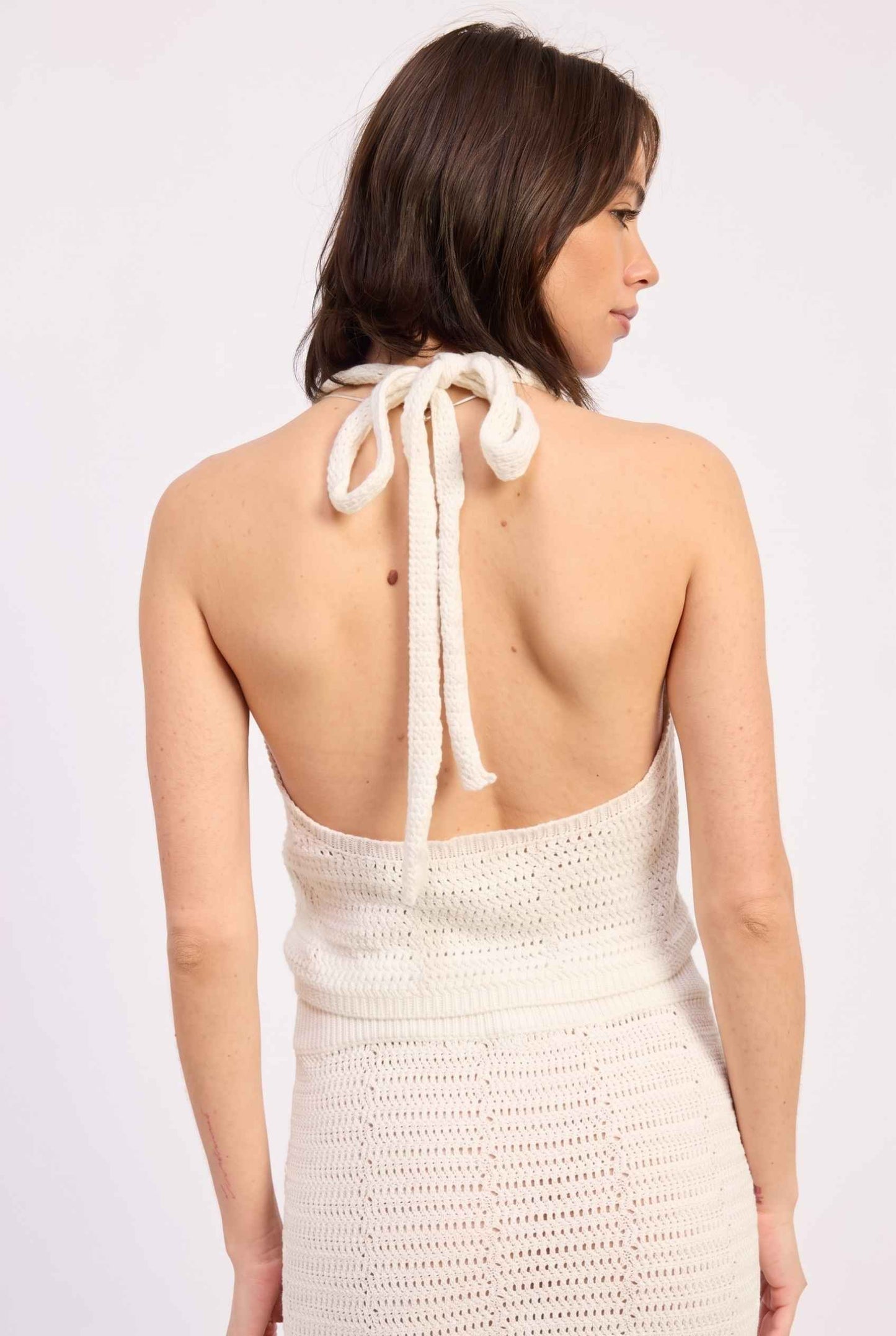 Model wearing Capri Floral Crochet Halter Top in Ivory Cotton Knit Crop Top with matching maxi skirt back view tie-up neck