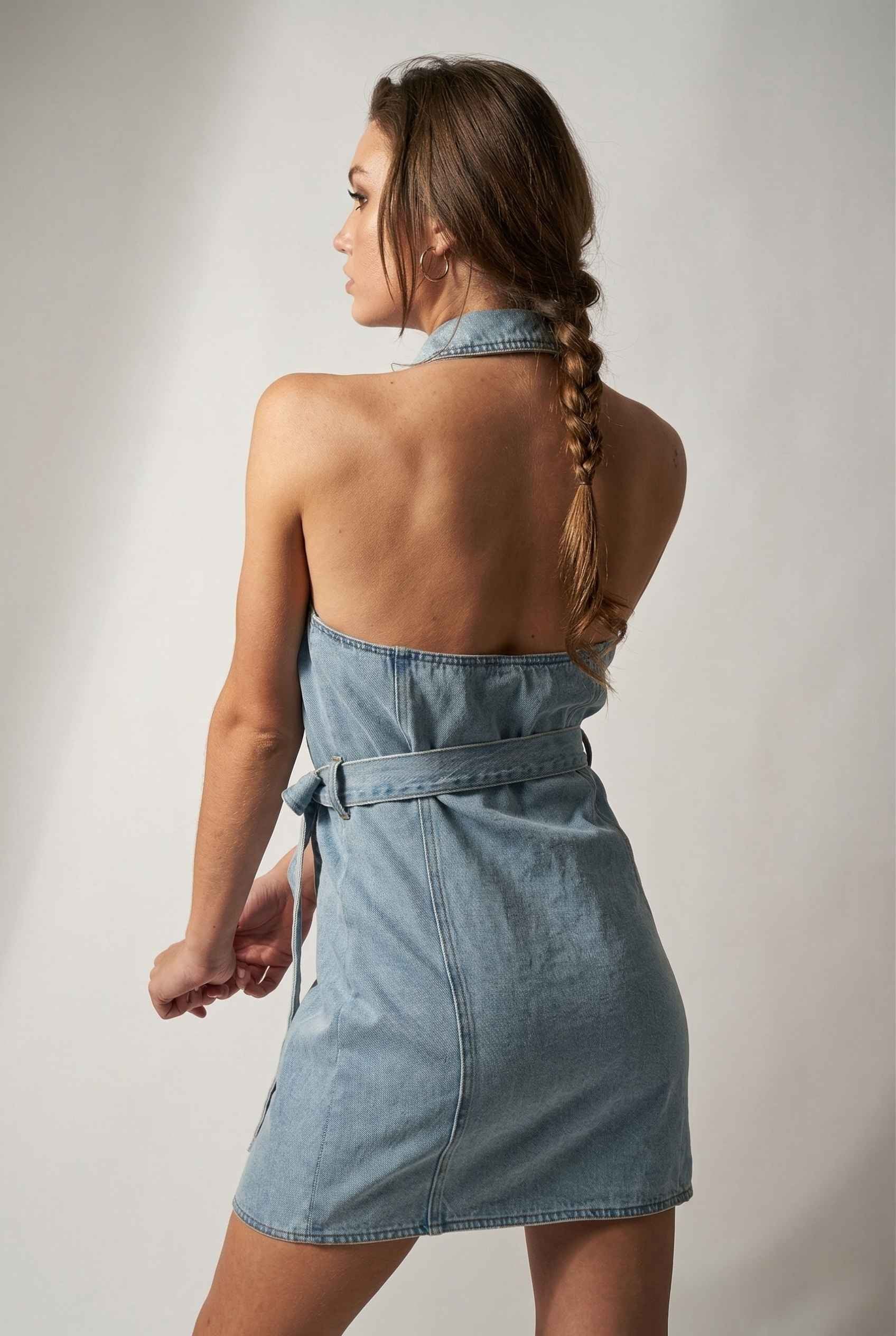 Model wearing Cassidy Mini in Light Wash Denim Button-Front Dress halter back open detail