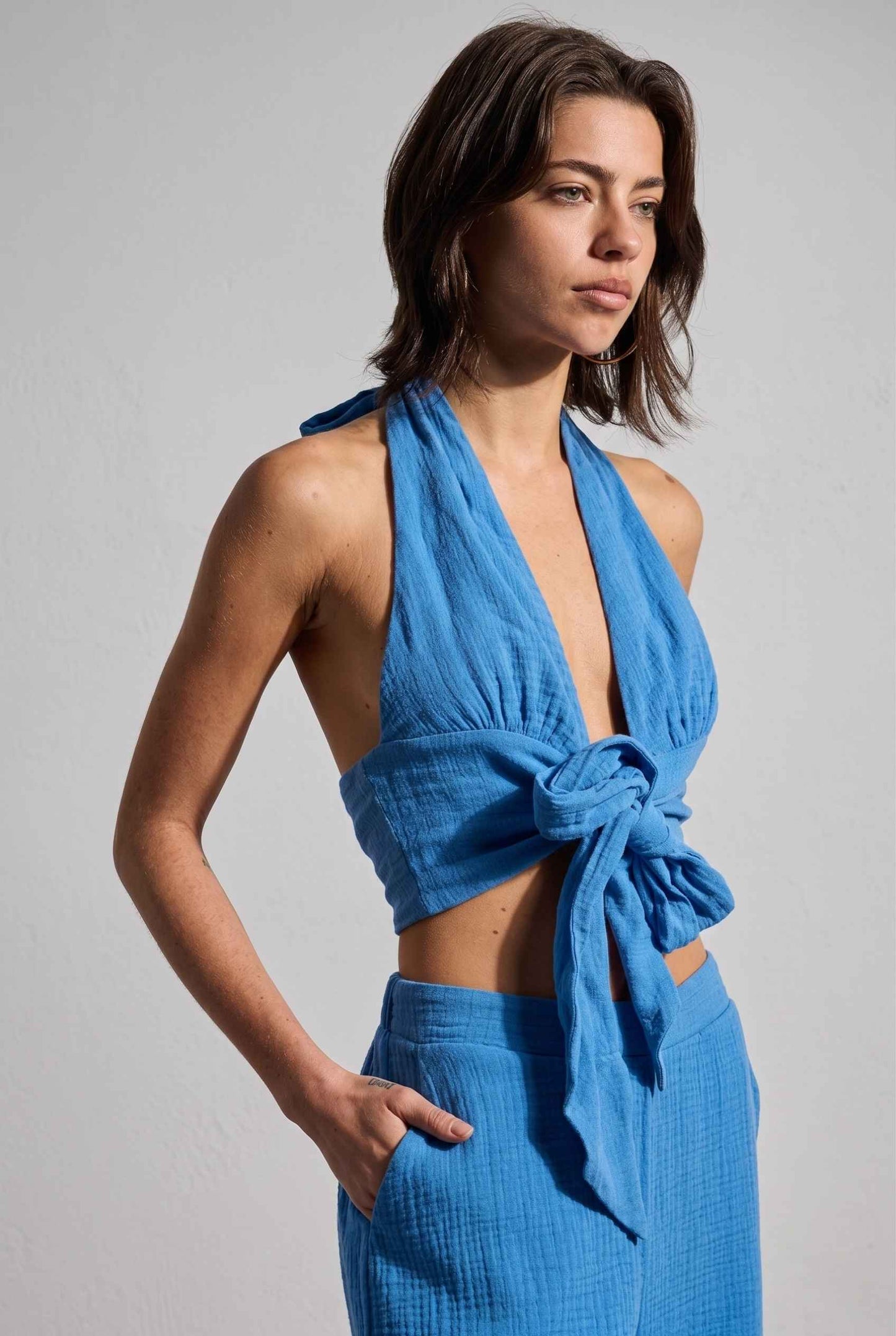Model wearing Celine Gauze Halter Crop Top 100% Cotton Tie-Front Top in Blue paired with matching high waisted pants tie front detail