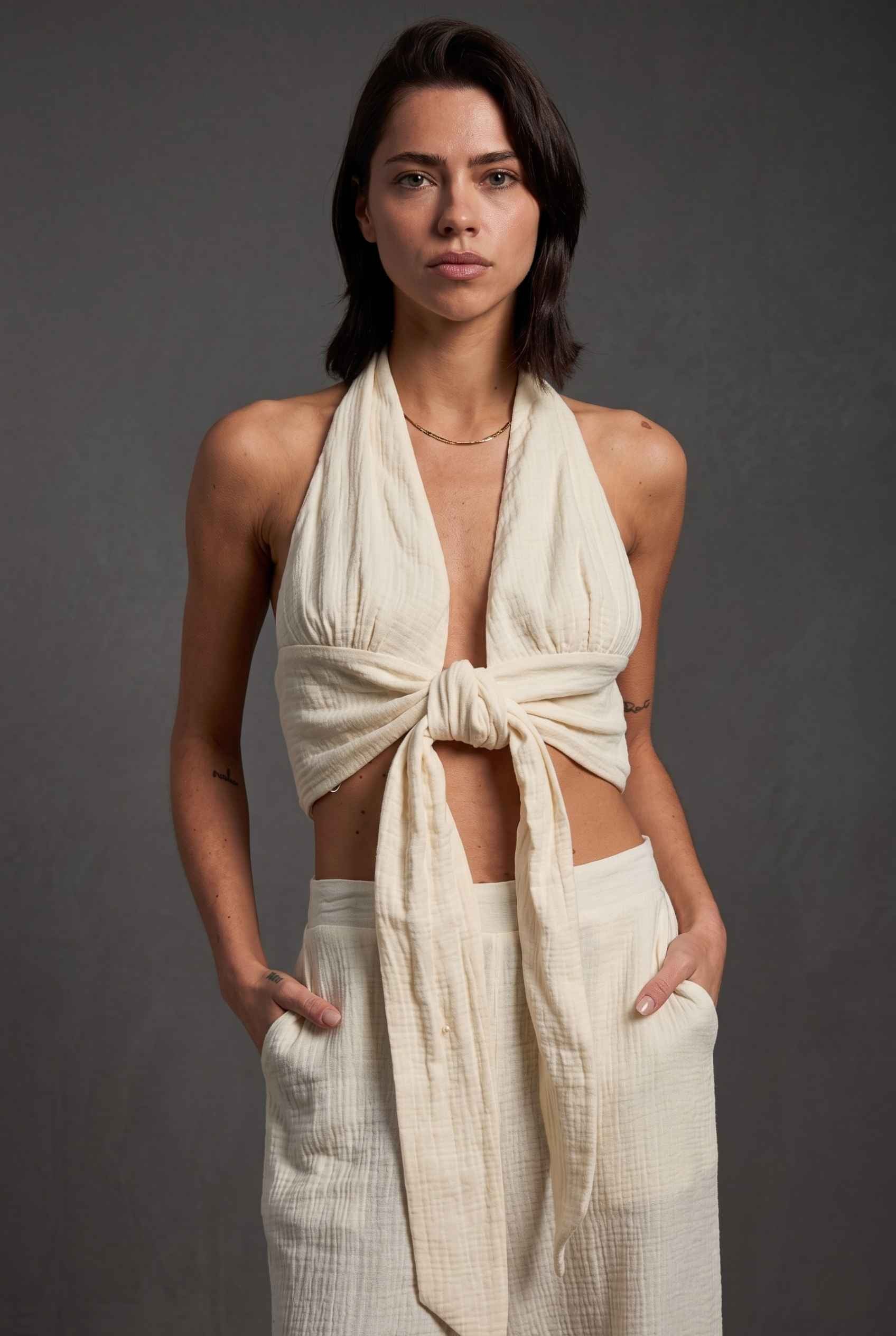Model wearing Celine Gauze Halter Crop Top 100% Cotton Tie-Front Top in Off White paired with matching high waisted pants large tie front and halter neckline detail