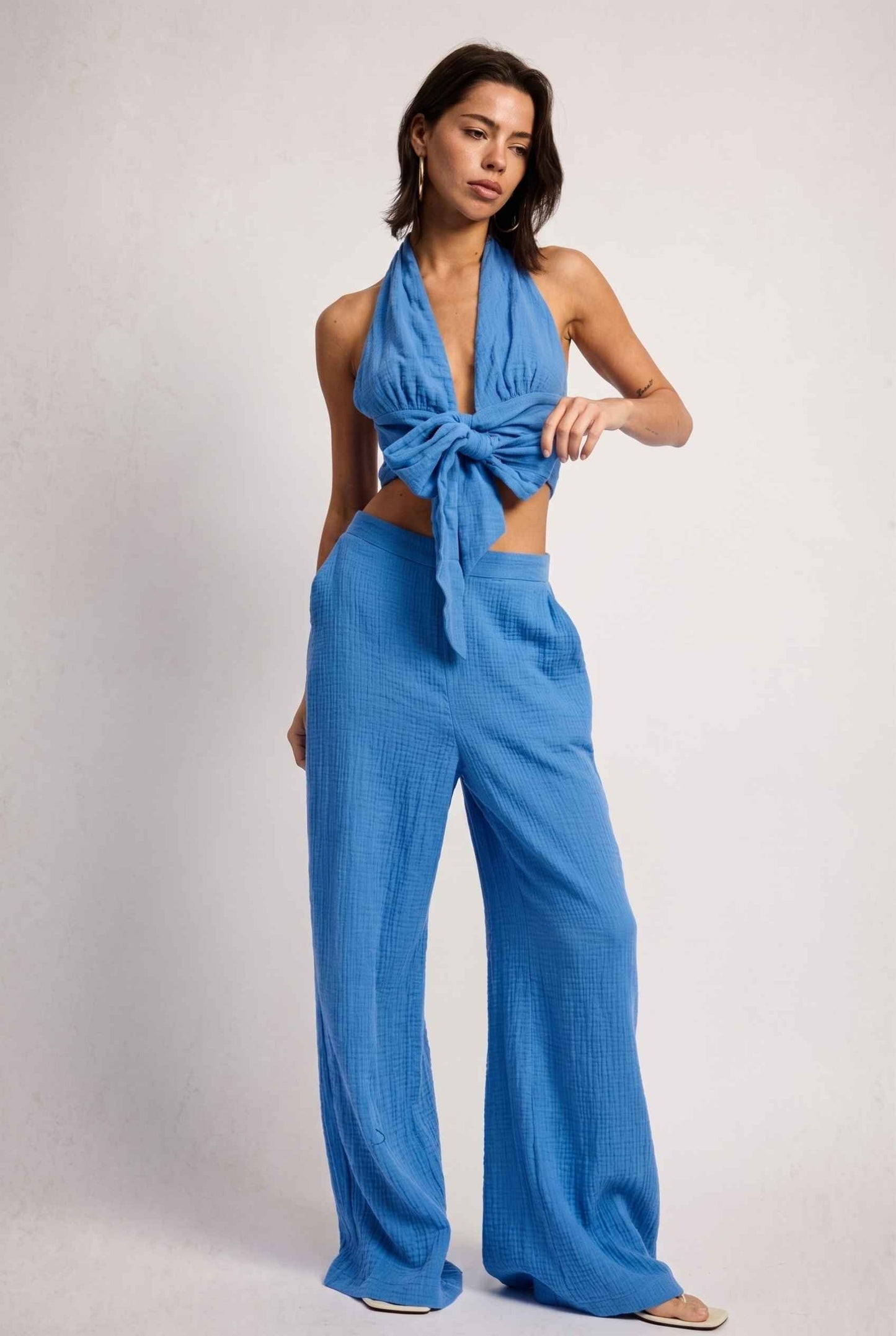 Model wearing Celine Gauze Halter Crop Top 100% Cotton Tie-Front Top in Blue paired with matching high waisted pants and sandals
