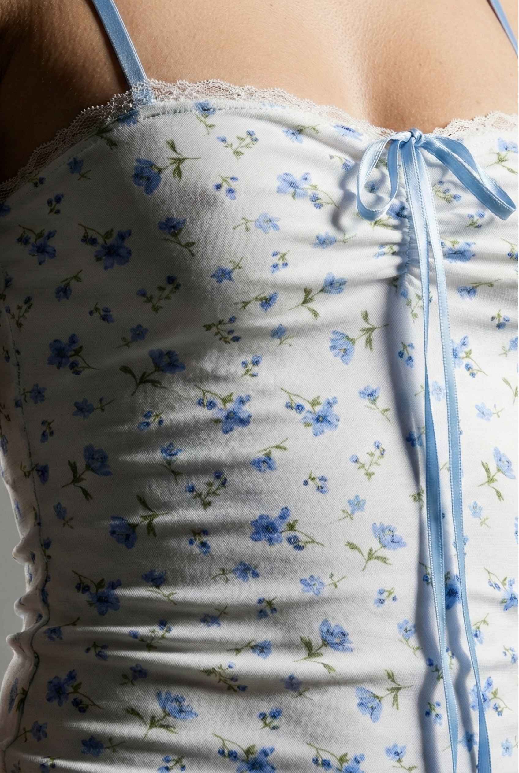 Chloe Mini Blue Floral Mesh Tie Front Dress with blue flowers on a person, close-up view.