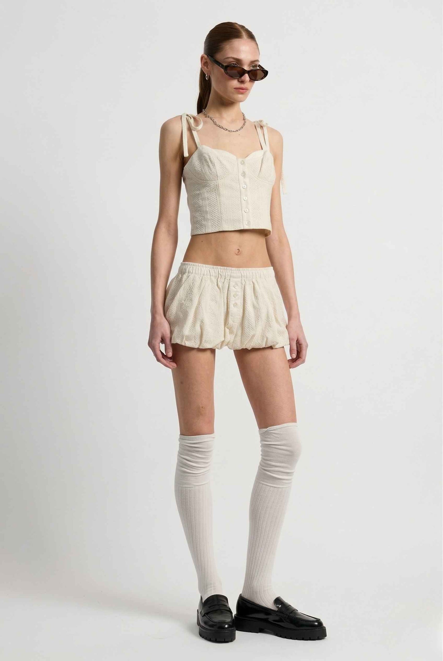 Woman wearing a Chloe Skirt Cream Cotton Eyelet Bubble Hem Mini Skirt and a top on a white background