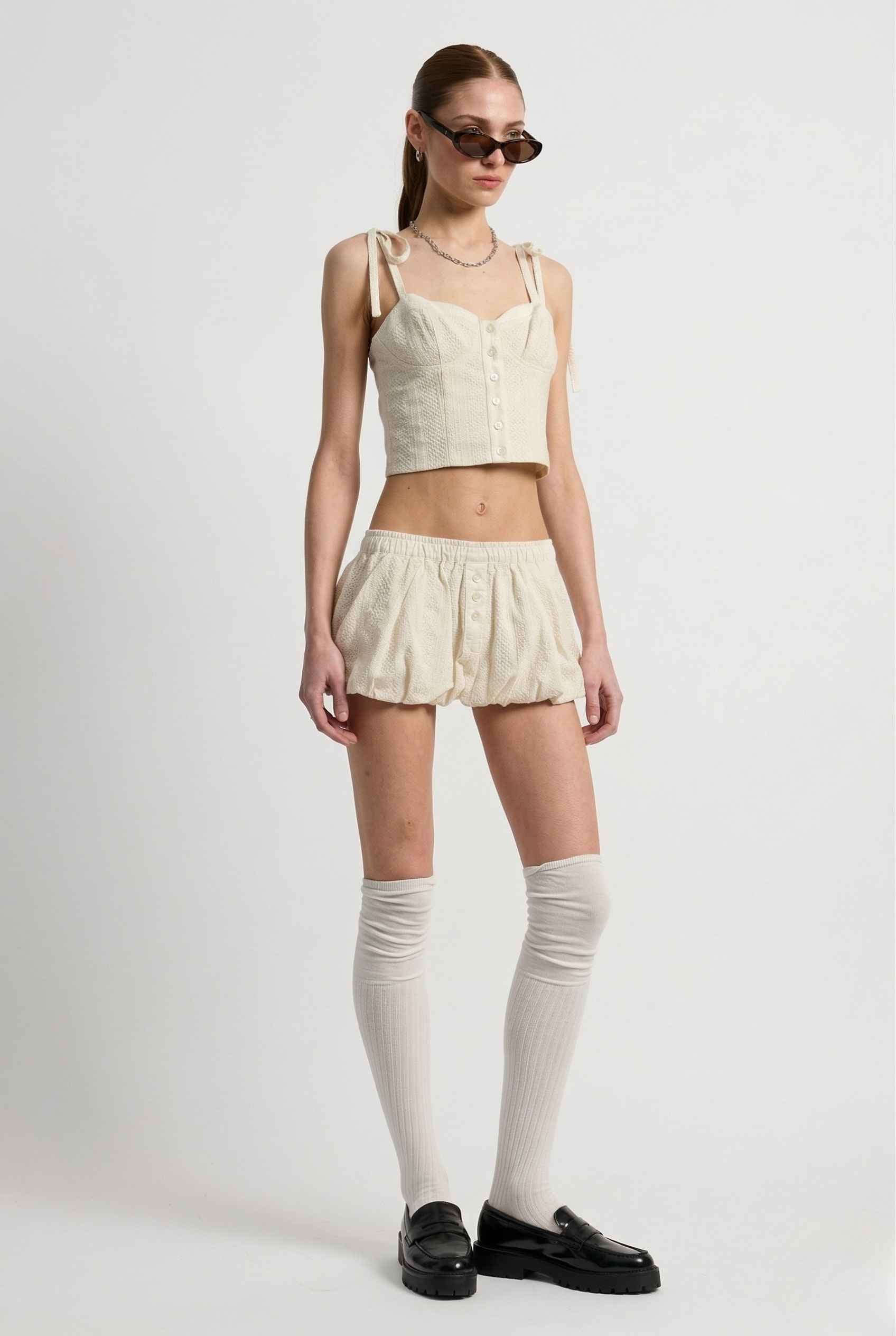 Woman wearing a Chloe Skirt Cream Cotton Eyelet Bubble Hem Mini Skirt and a top on a white background