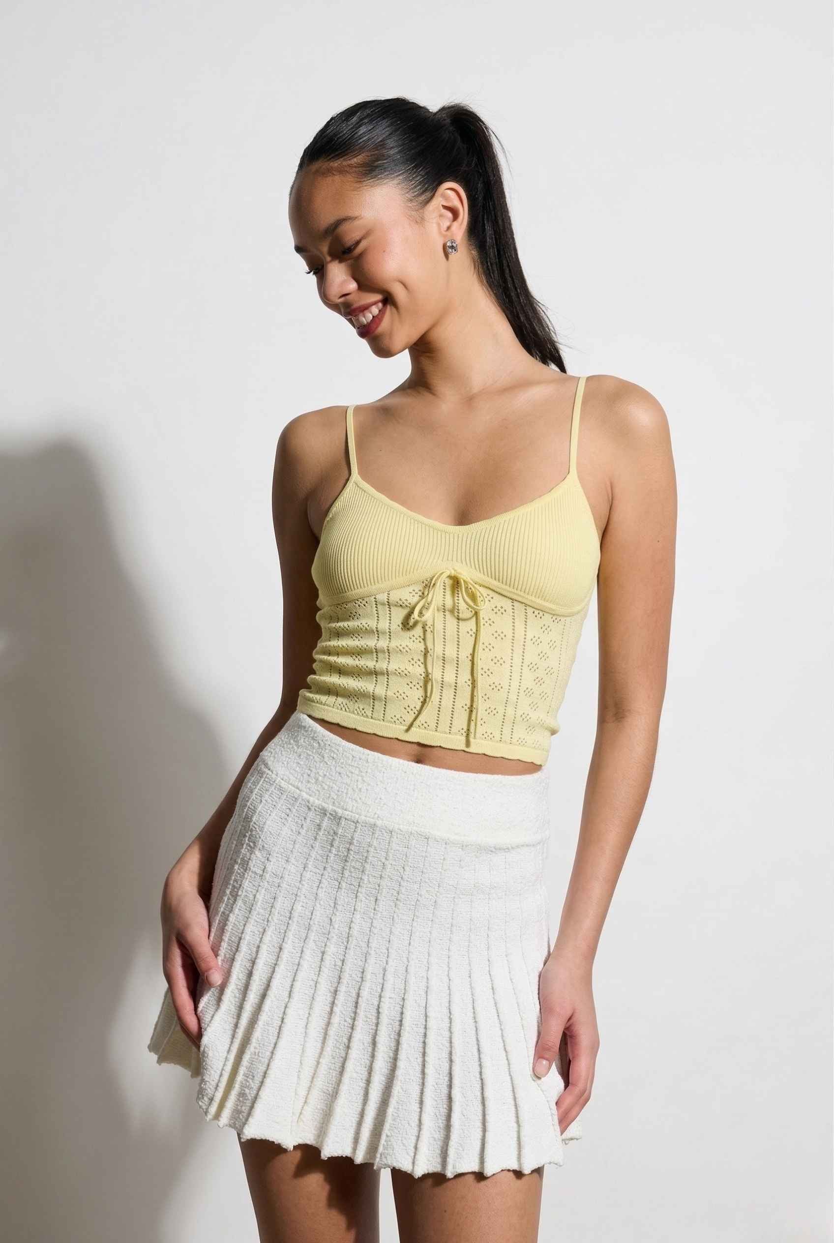 Woman wearing a yellow top and Chloe Skirt Textured Knit Pleated Mini Skirt in White against a plain background