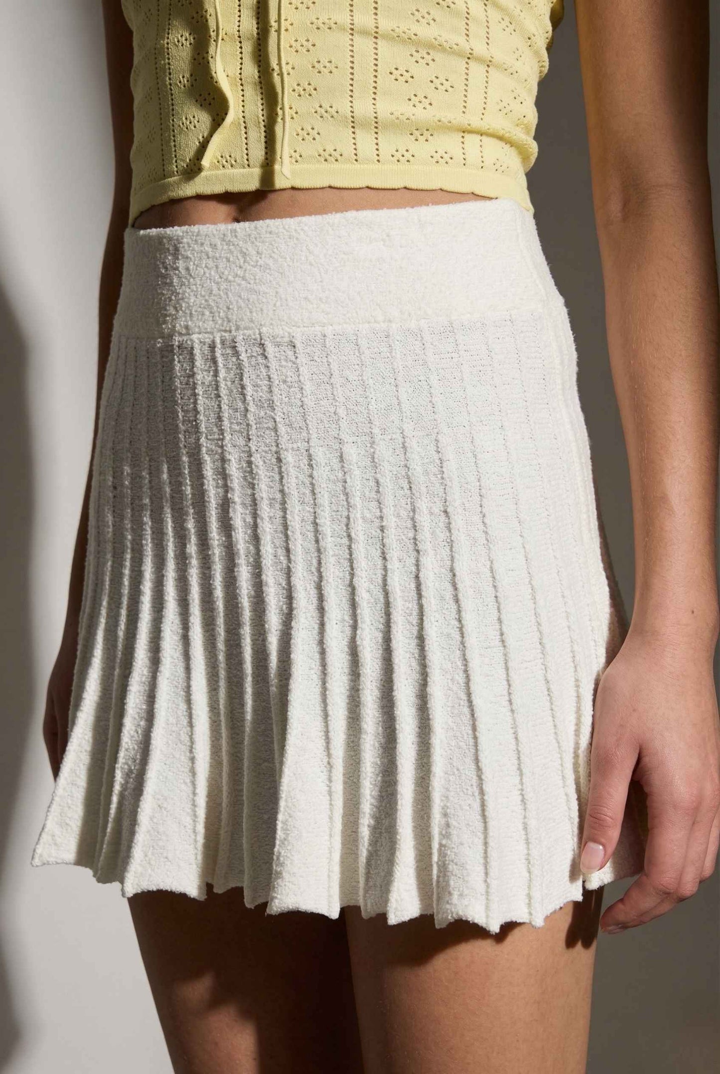 Chloe Skirt Textured Knit Pleated Mini Skirt in White worn with a yellow top against a neutral background