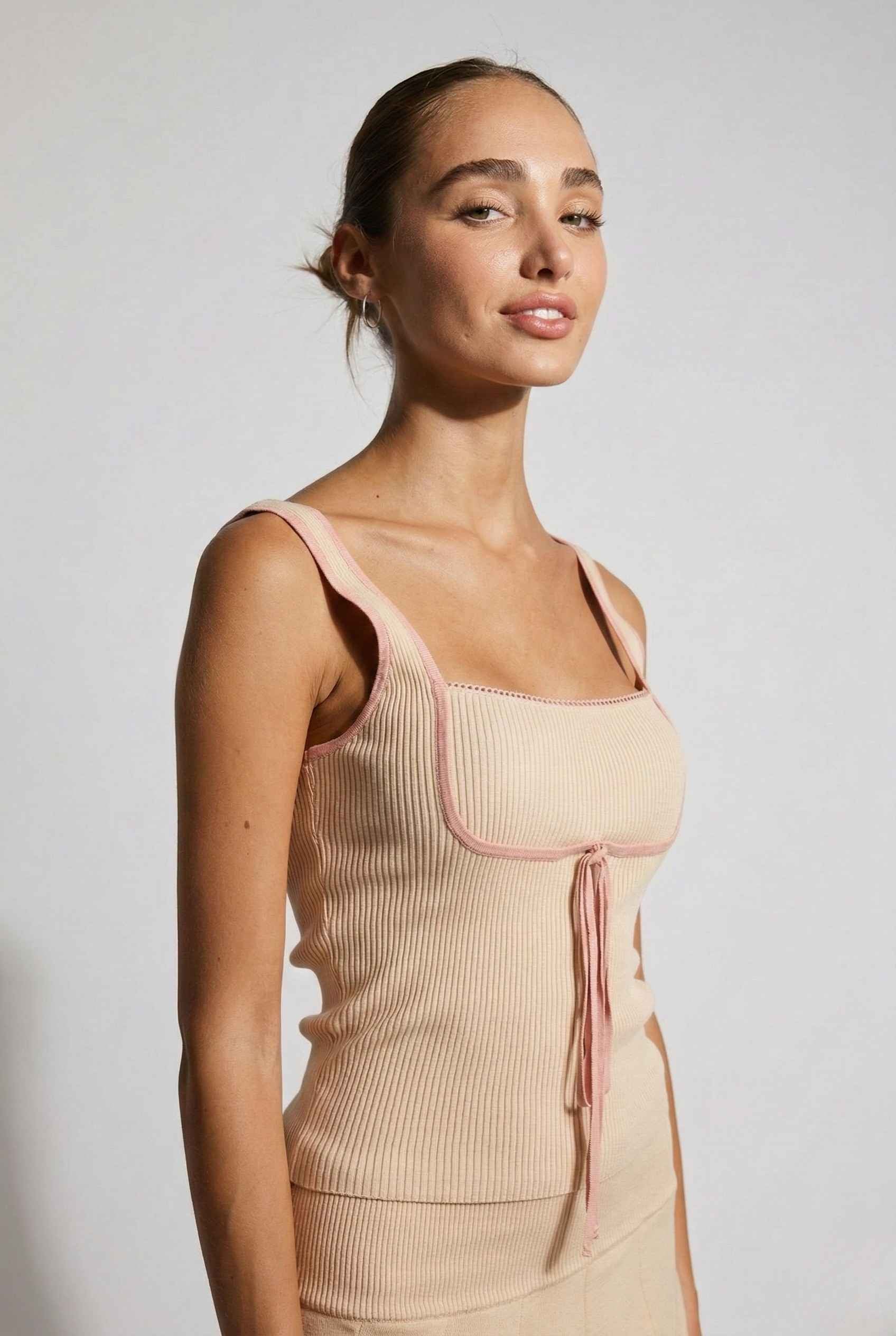 Woman wearing a Chloe Top Beige Contrast Trim Ribbed Knit Tank with pink accents against a plain background