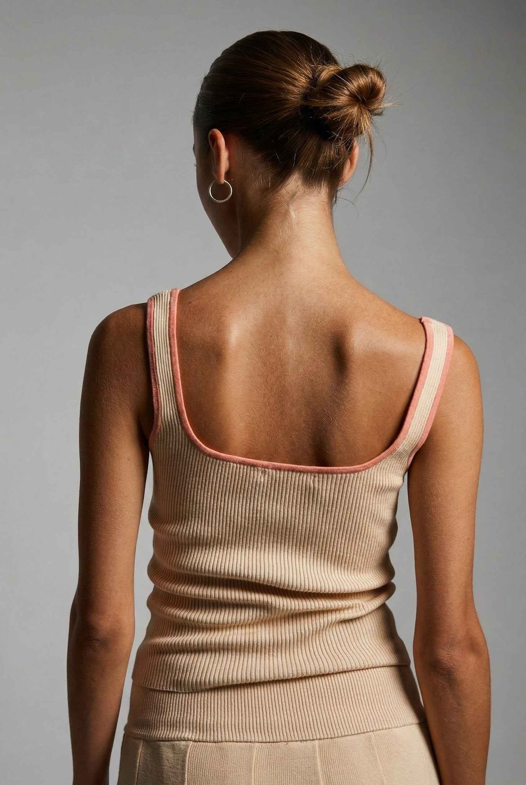 Woman wearing a Chloe Top Beige Contrast Trim Ribbed Knit Tank with pink trim on a gray background