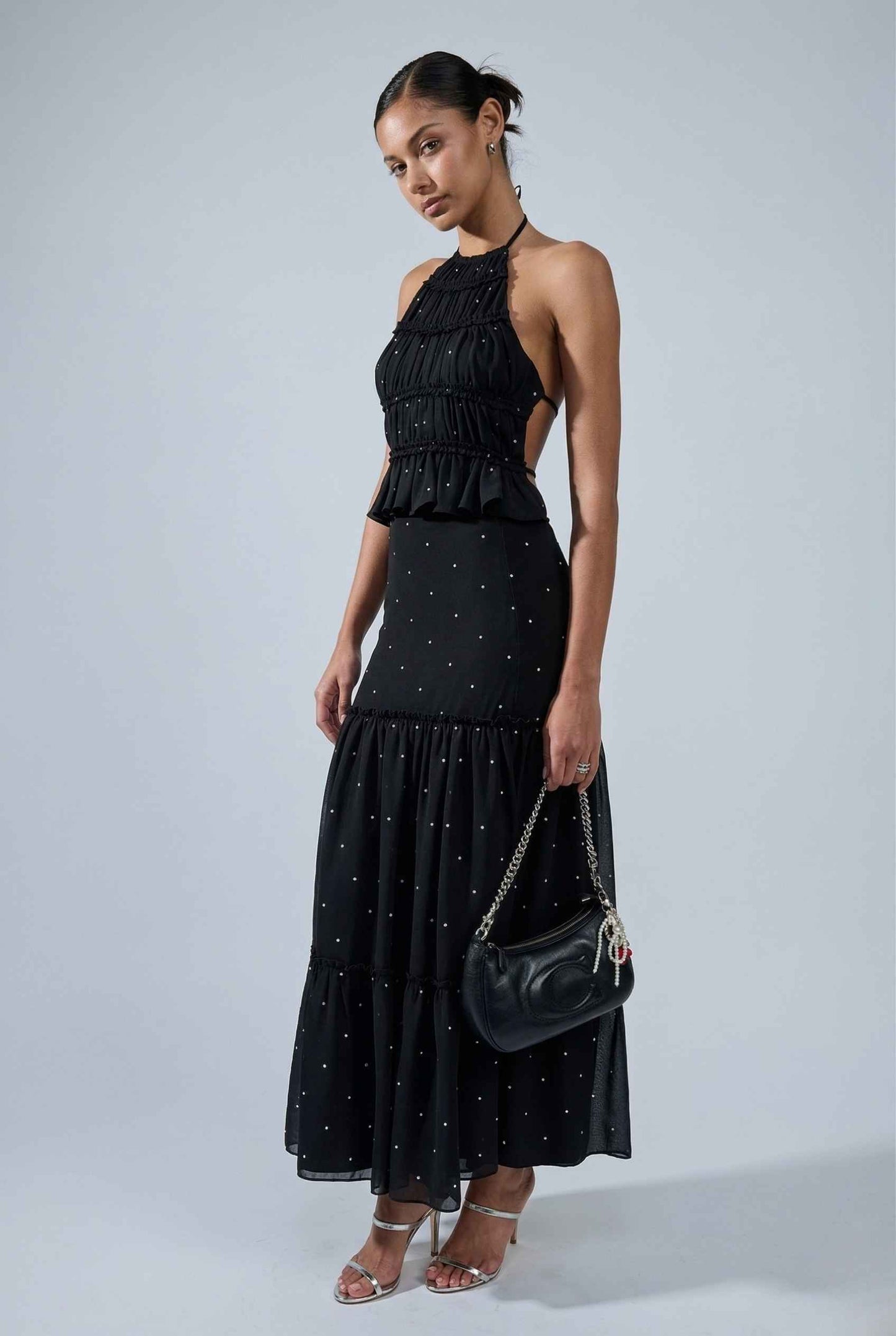 Woman wearing a Clara Skirt Black Tiered Ruffle Polka Dot Midi Skirt with a polka dot pattern on a gray background