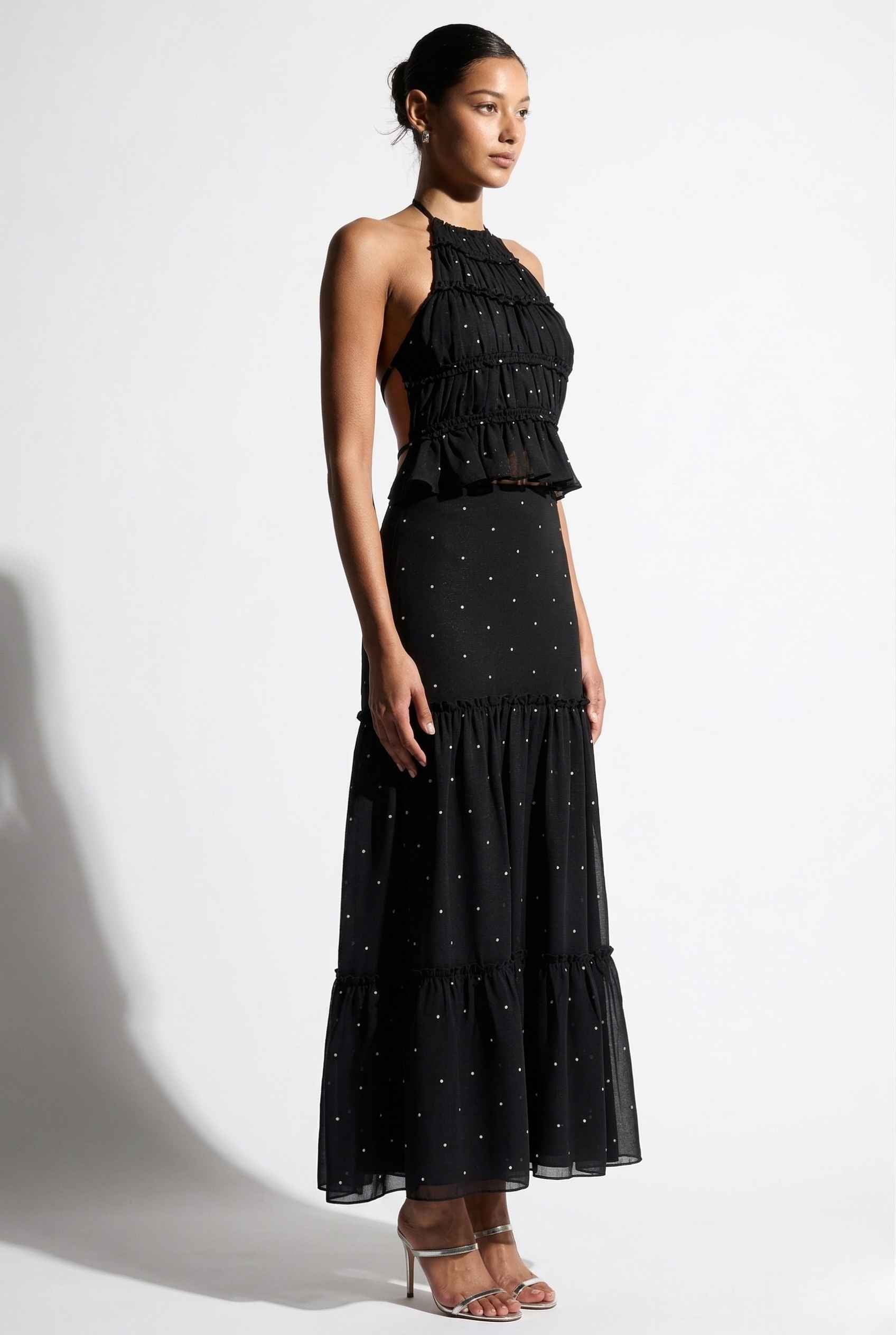 Woman wearing a Clara Skirt Black Tiered Ruffle Polka Dot Midi Skirt with a plain background