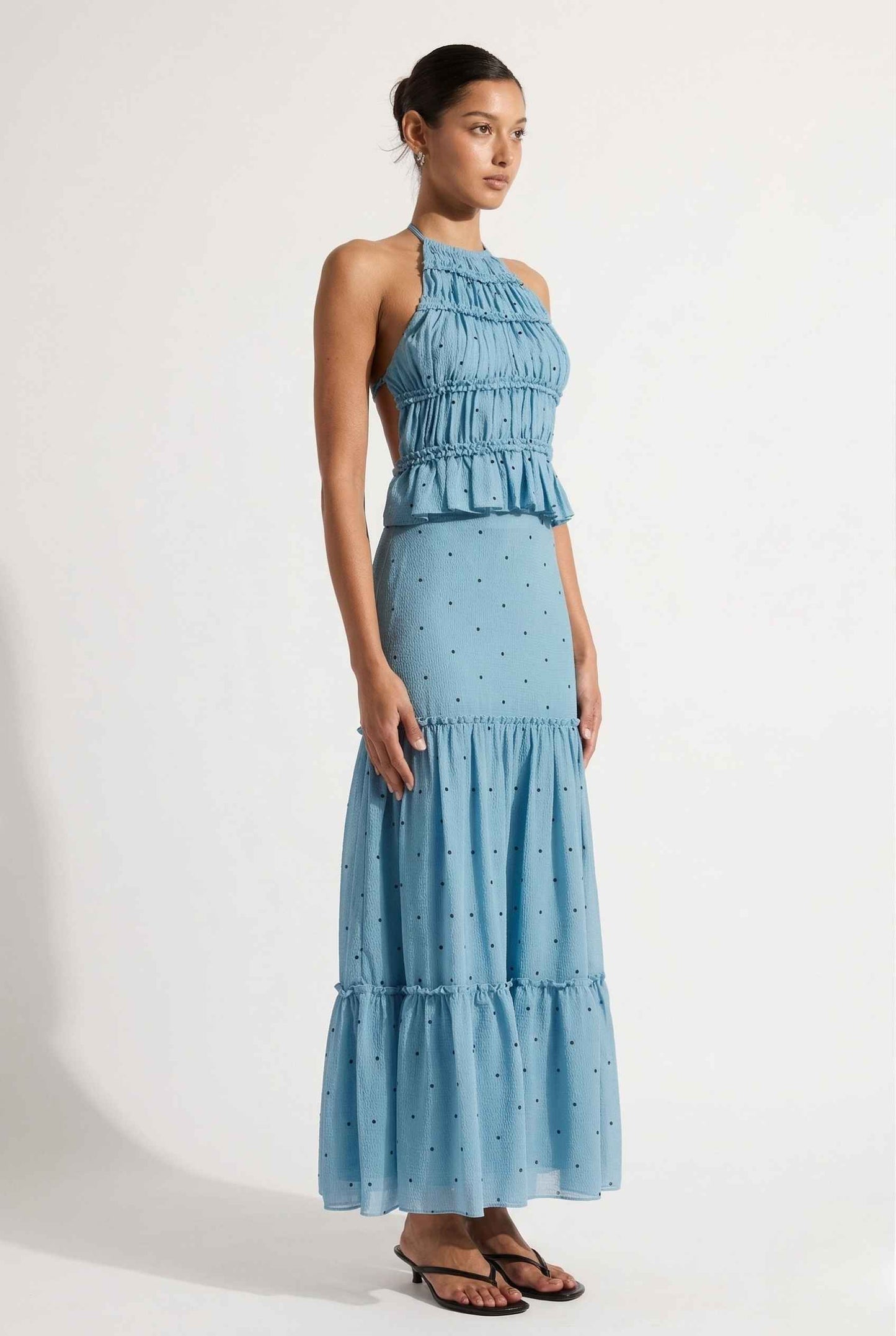 Woman wearing a Clara Skirt Blue Tiered Ruffle Polka Dot Midi Skirt with a plain background