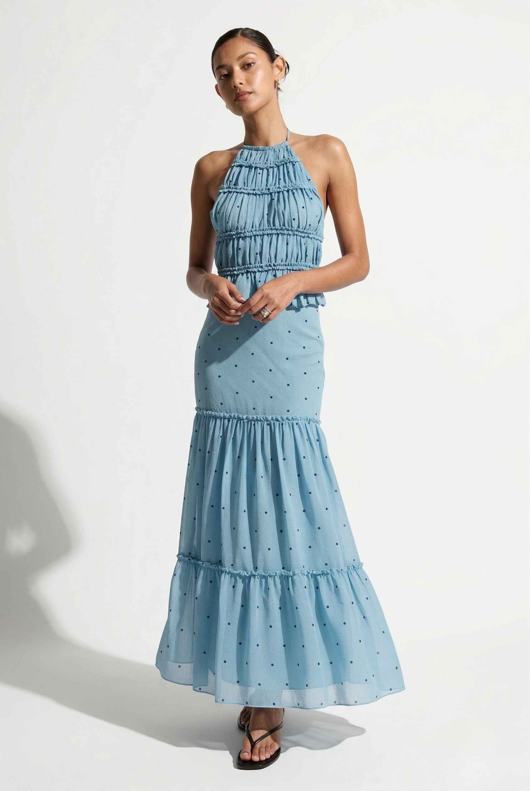 Woman wearing a Clara Skirt Blue Tiered Ruffle Polka Dot Midi Skirt on a plain background