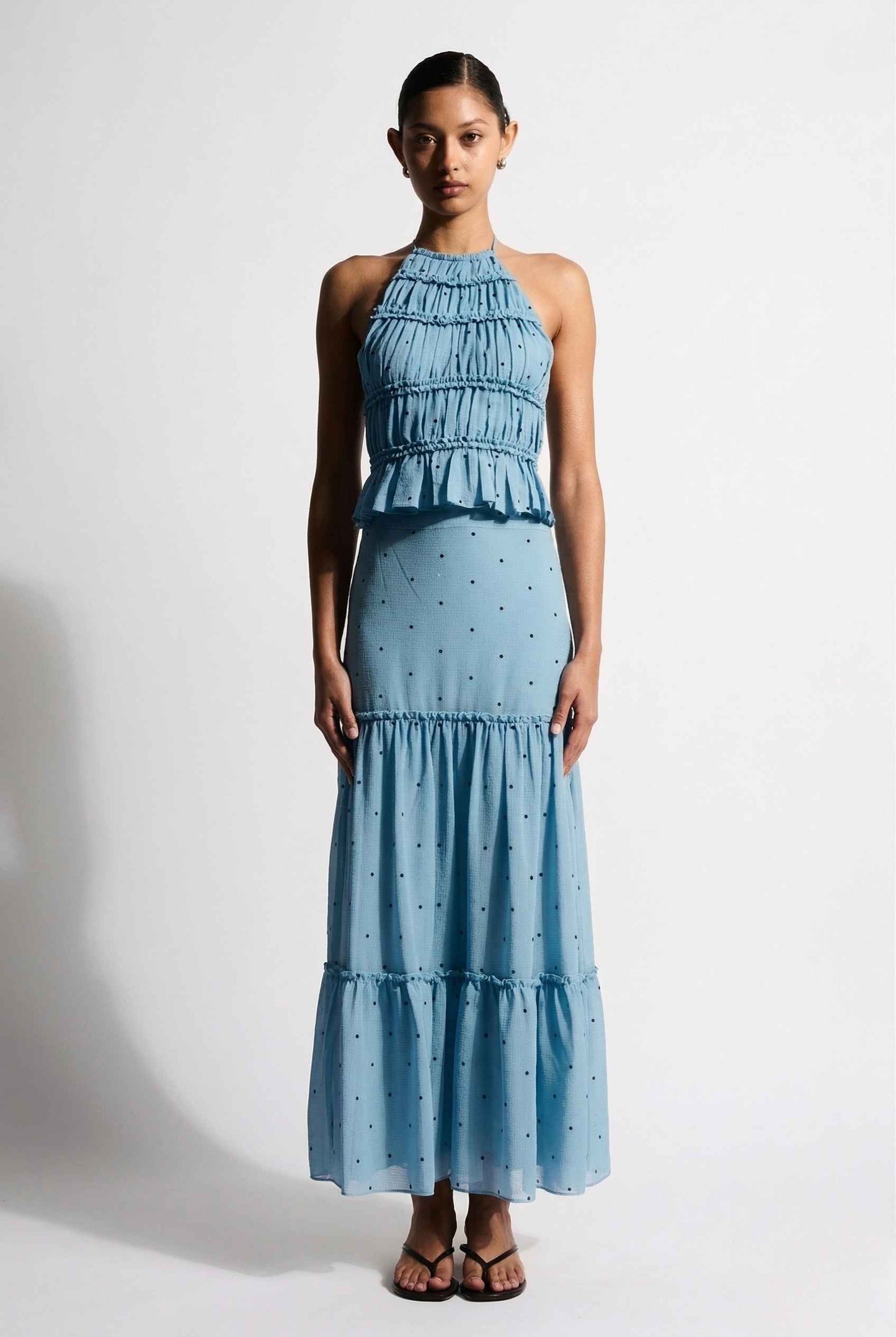 Woman wearing a Clara Skirt Blue Tiered Ruffle Polka Dot Midi Skirt against a plain background