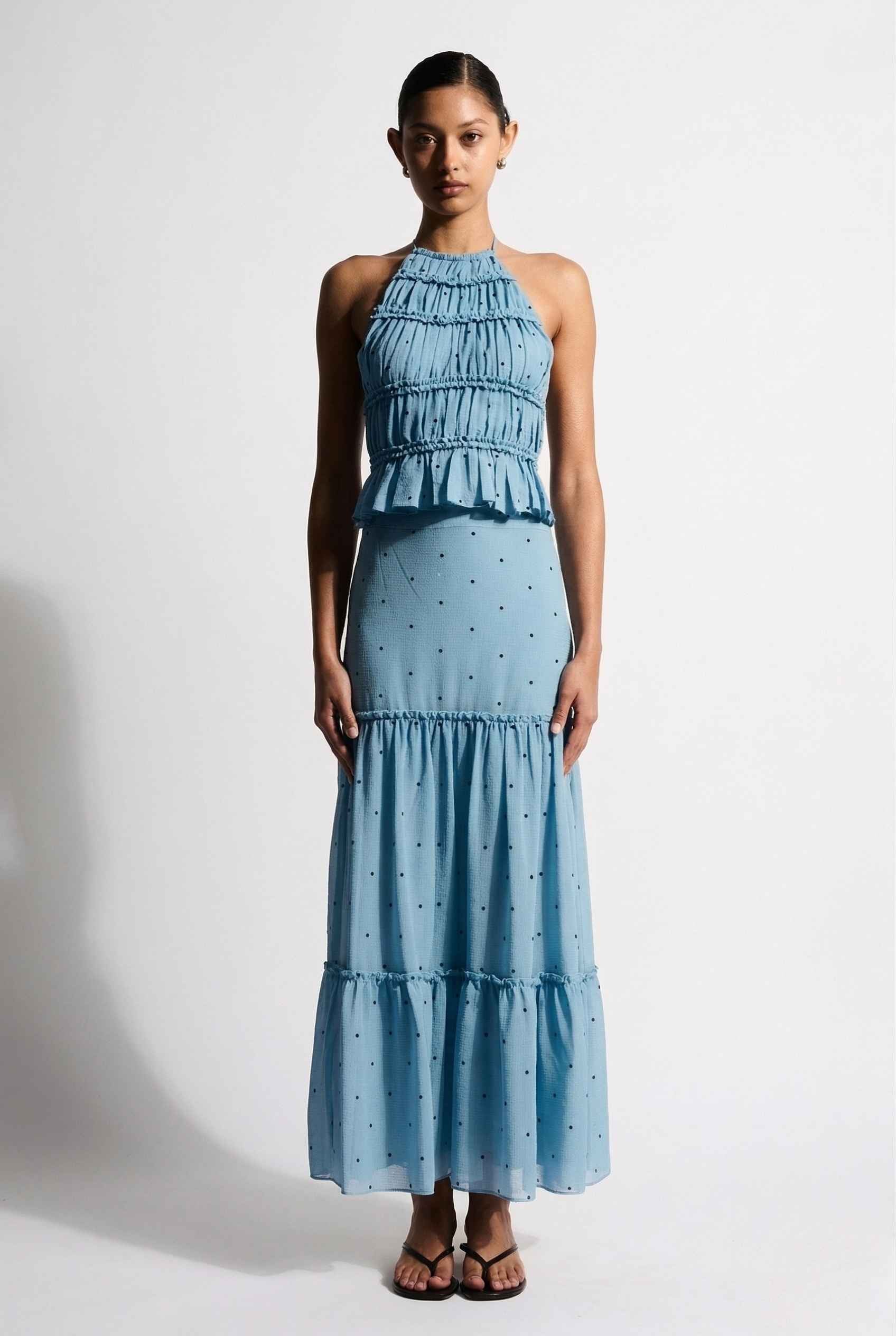 Woman wearing a Clara Skirt Blue Tiered Ruffle Polka Dot Midi Skirt against a plain background