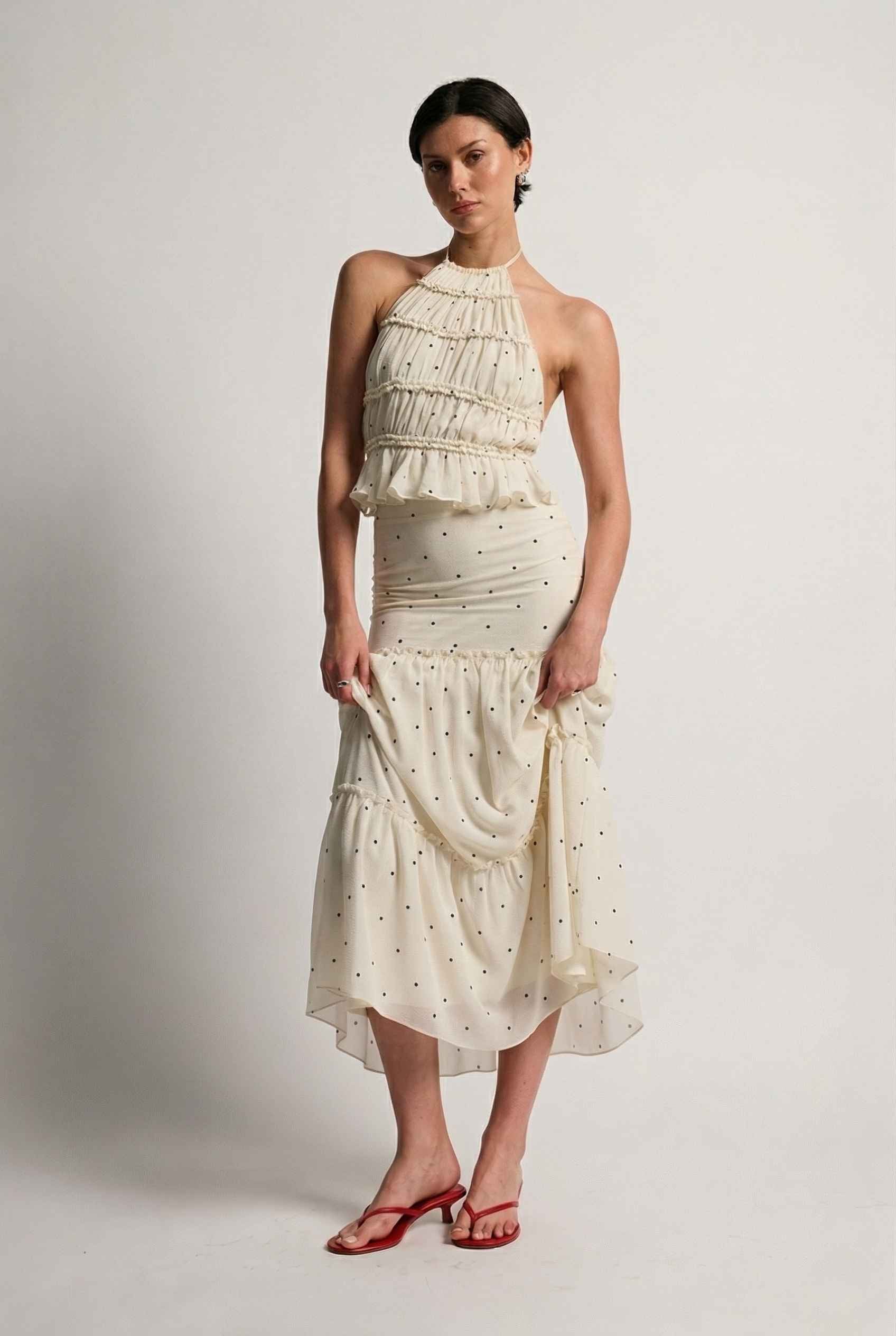 Woman wearing a Clara Skirt White Tiered Ruffle Polka Dot Midi Skirt on a plain background