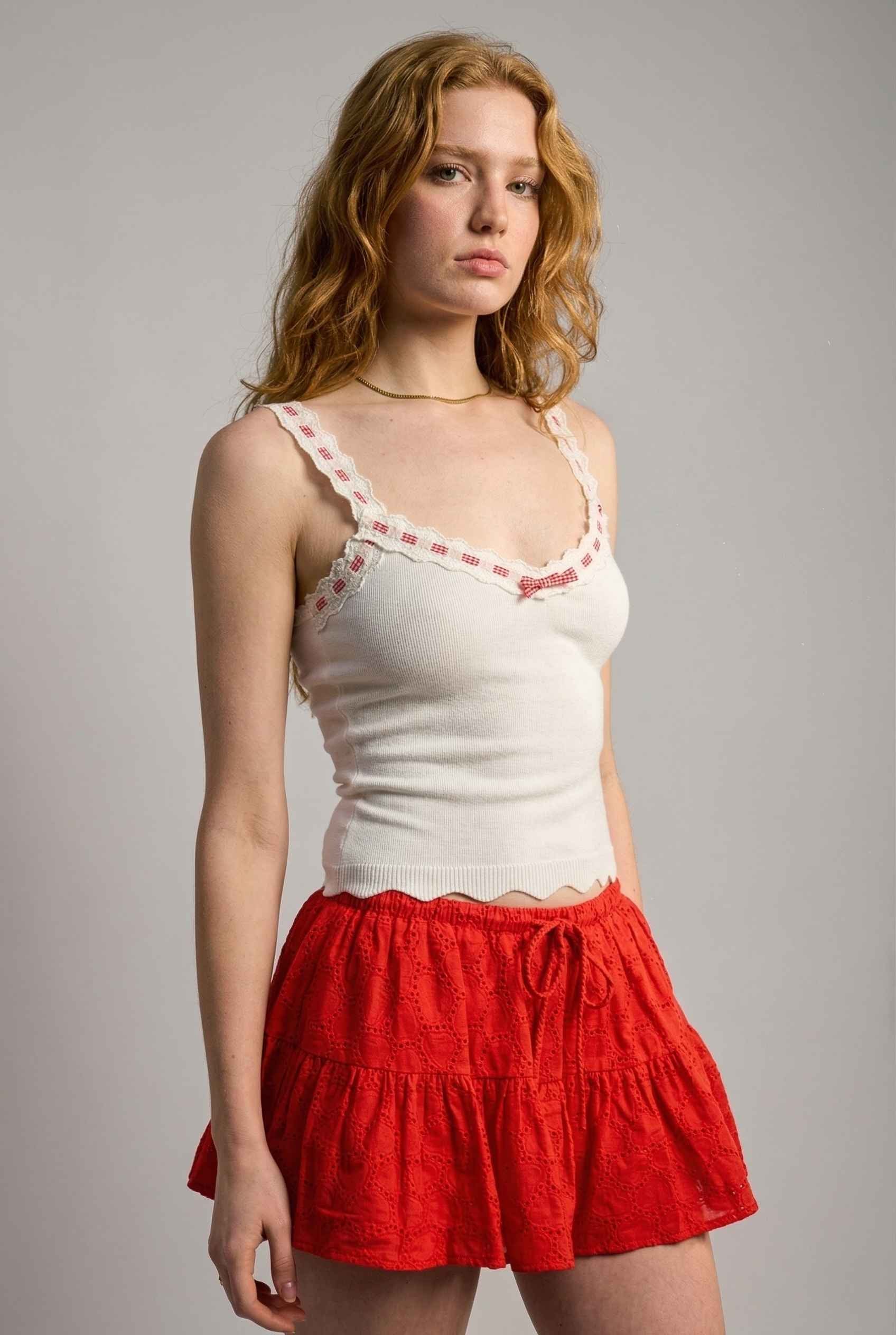 Model wearing Clara Top in White Knit Tank with Scallop Trim & Bow paired with ruffle mini skirt 