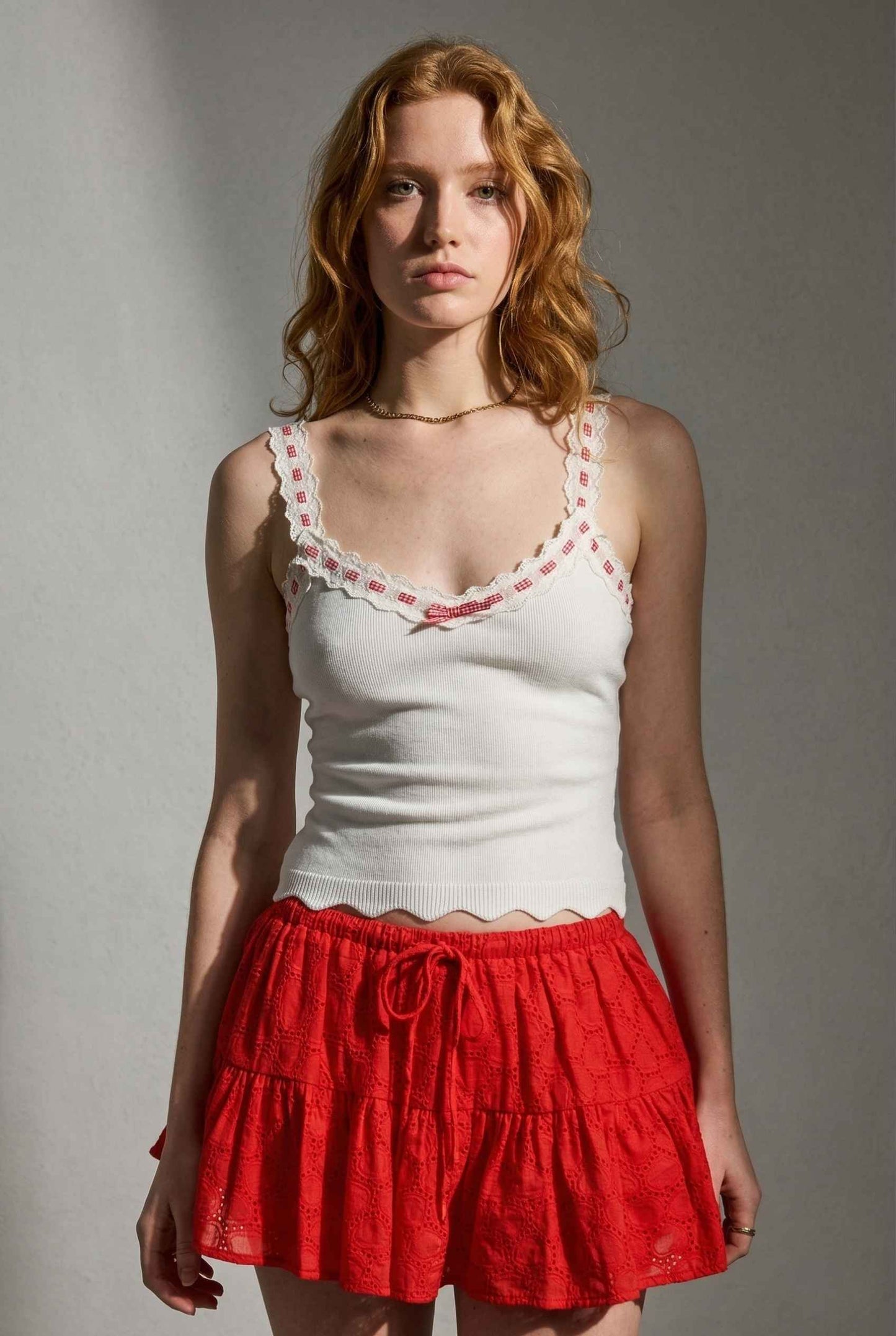 Model wearing Clara Top in White Knit Tank with Scallop Trim & Bow paired with ruffle mini skirt