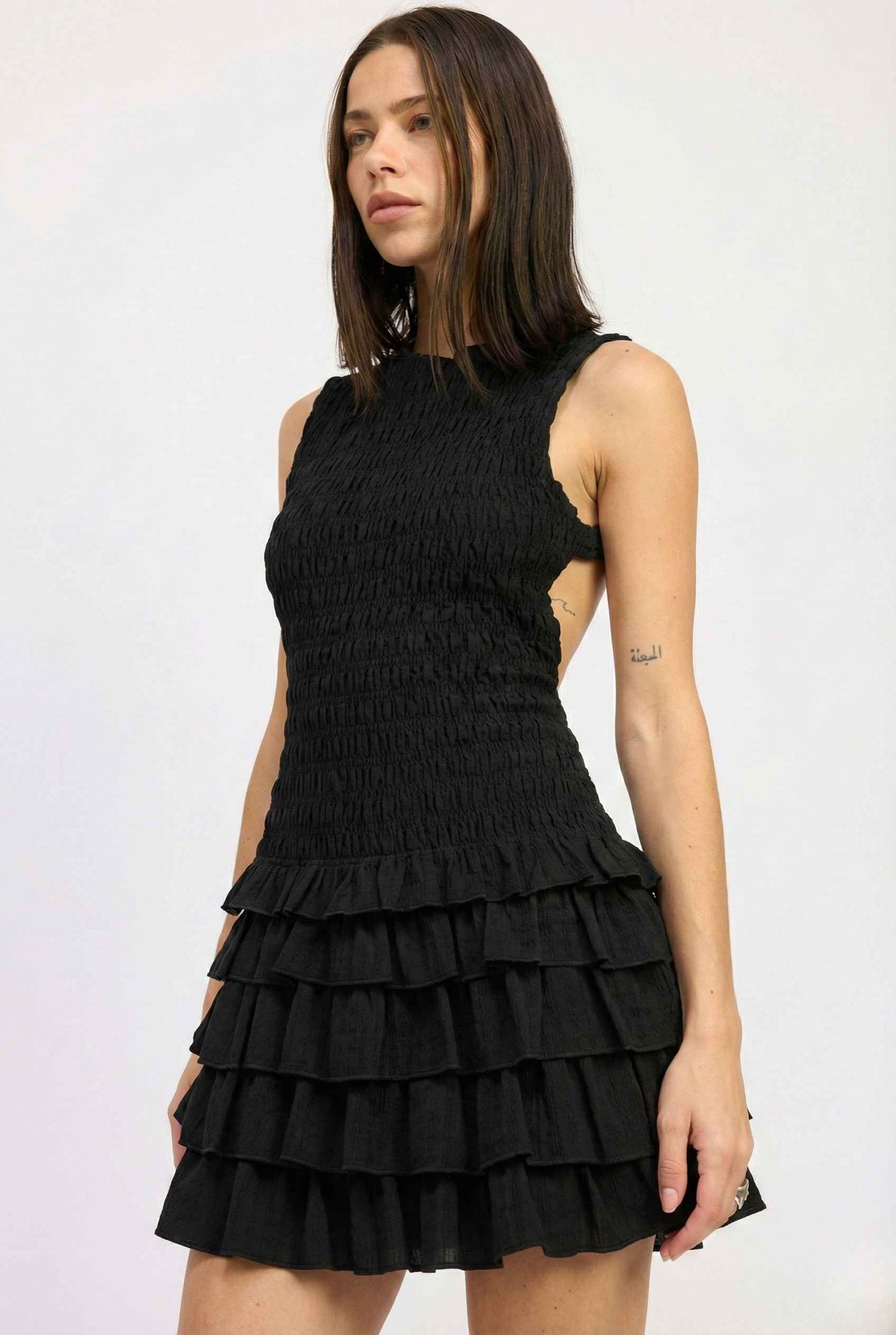 Woman wearing a Cleo Mini Black Smocked Ruffle Sleeveless Dress on a white background