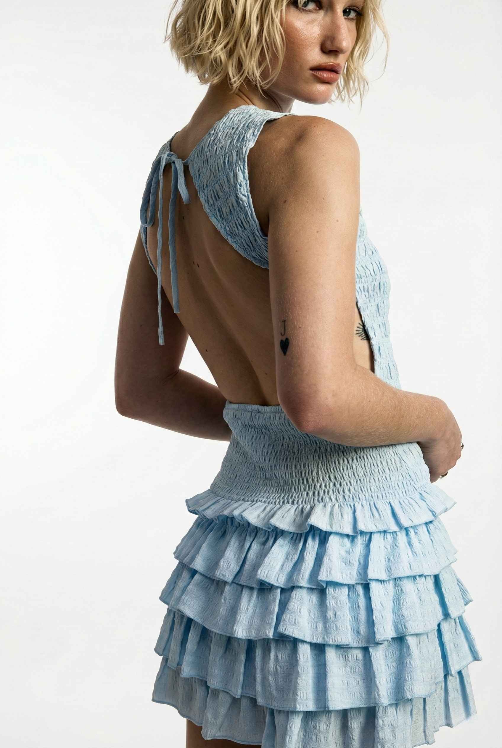 Cleo Mini Light Blue Smocked Ruffle Sleeveless Dress worn by a model on a white background