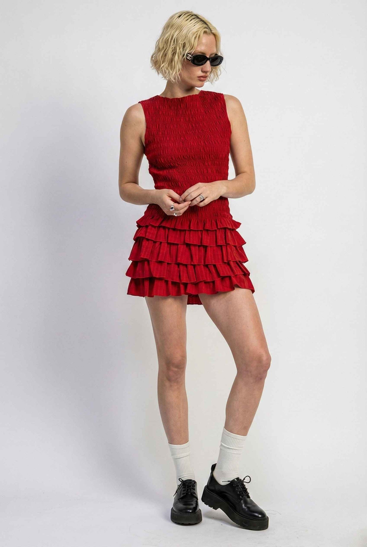 Person wearing a Cleo Mini Red Smocked Ruffle Sleeveless Dress with ruffled layers on a white background