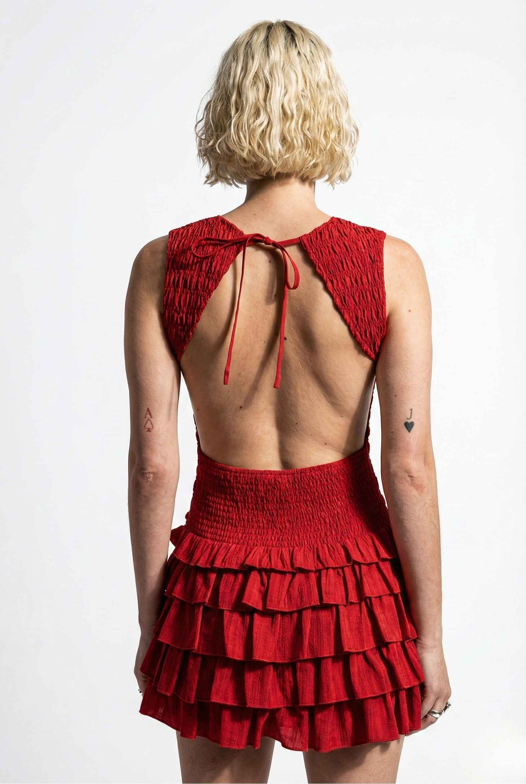 Person wearing a Cleo Mini Red Smocked Ruffle Sleeveless Dress with a tiered skirt and open back on a white background