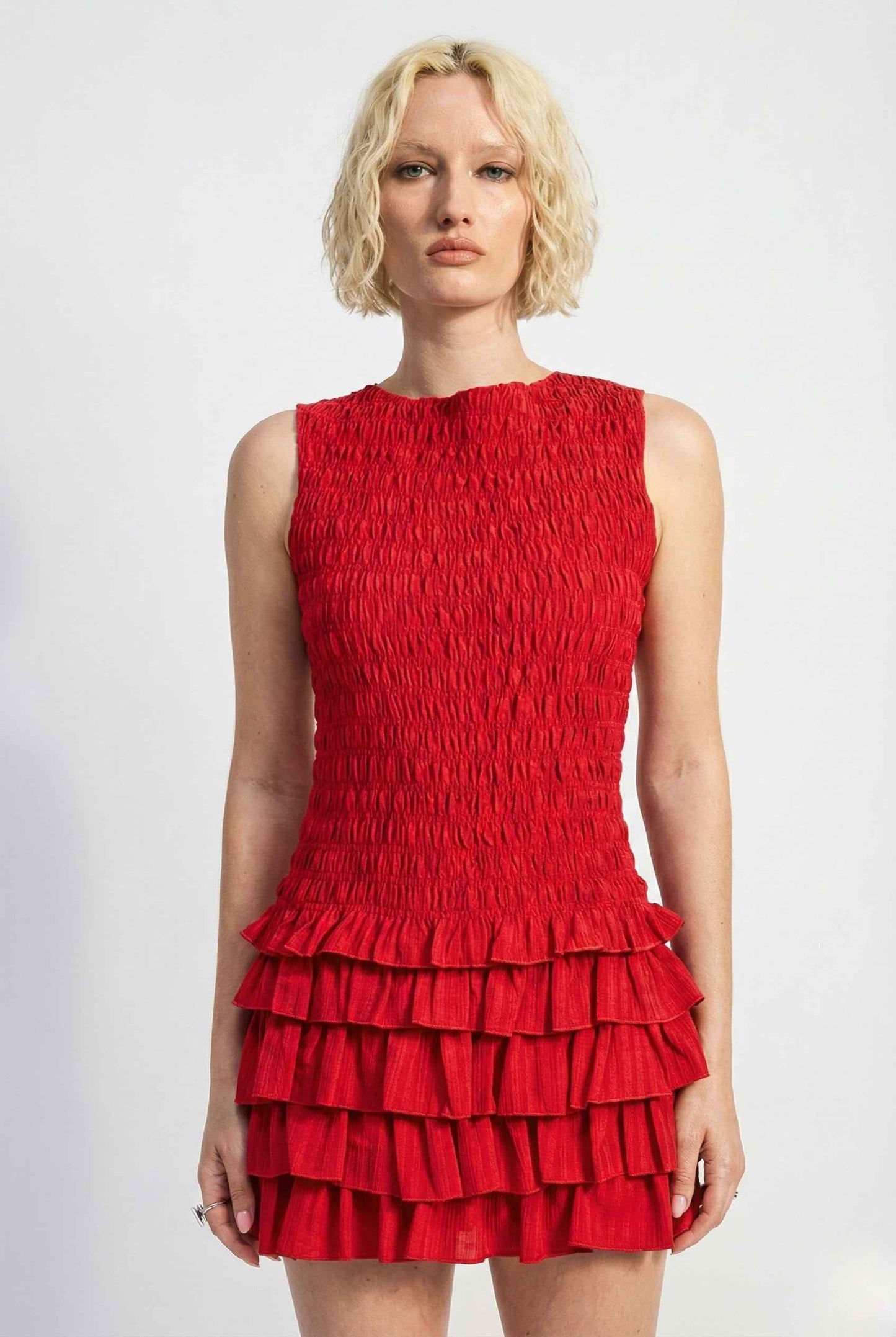 Woman wearing a Cleo Mini Red Smocked Ruffle Sleeveless Dress against a white background