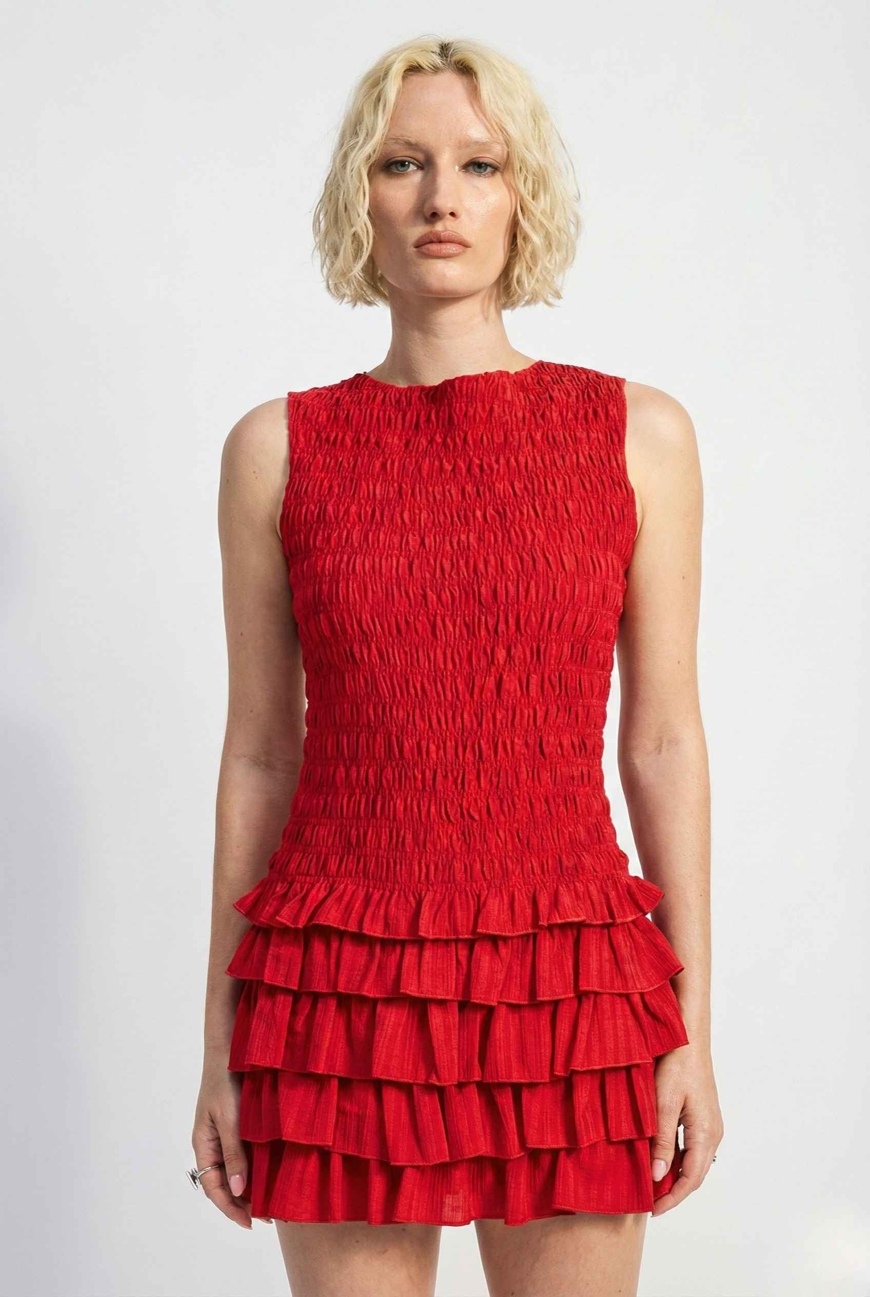 Woman wearing a Cleo Mini Red Smocked Ruffle Sleeveless Dress against a white background