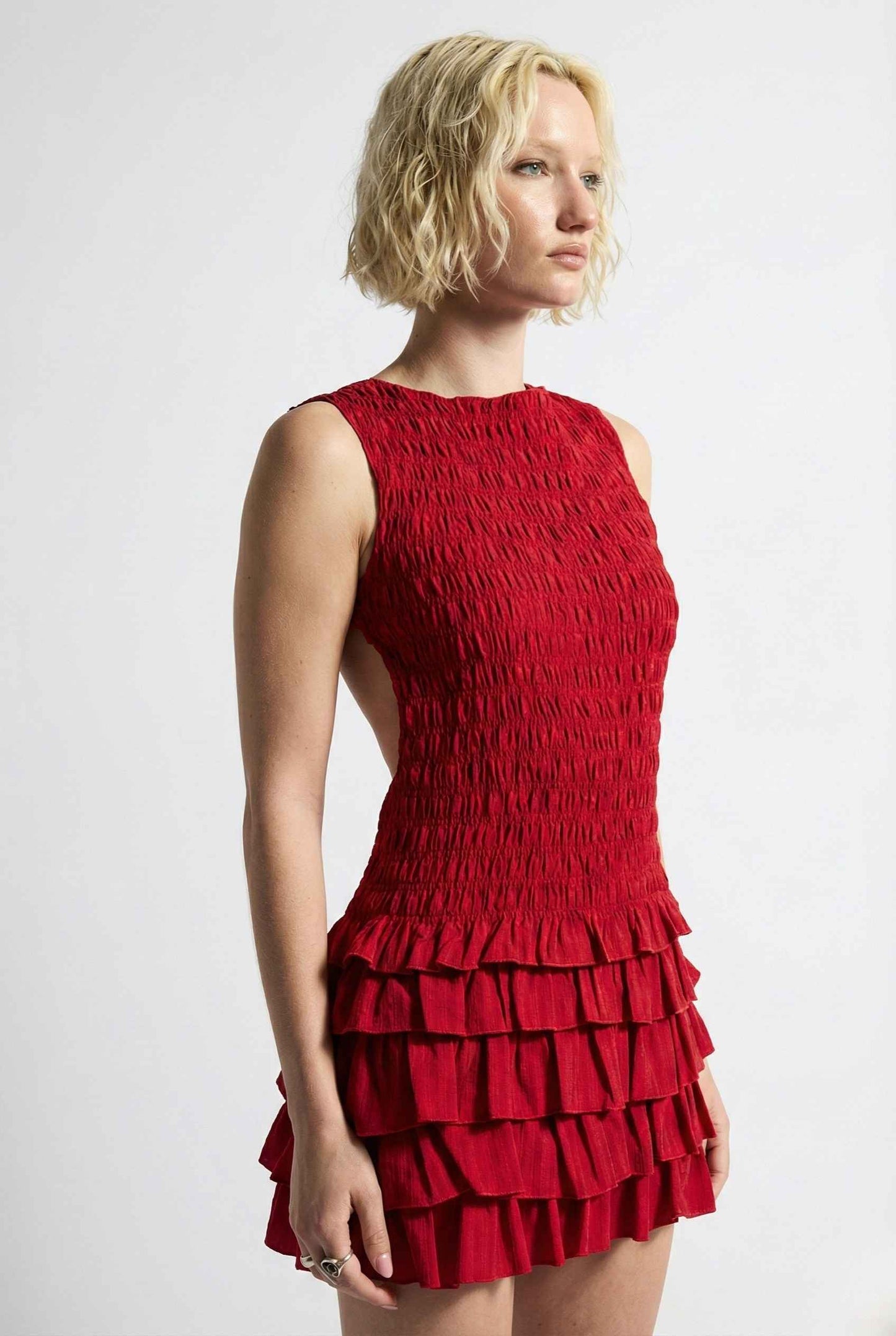 Woman wearing a Cleo Mini Red Smocked Ruffle Sleeveless Dress against a white background