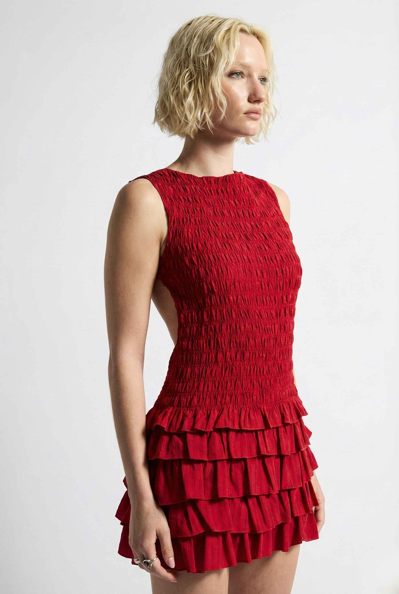 Woman wearing a Cleo Mini Red Smocked Ruffle Sleeveless Dress against a white background